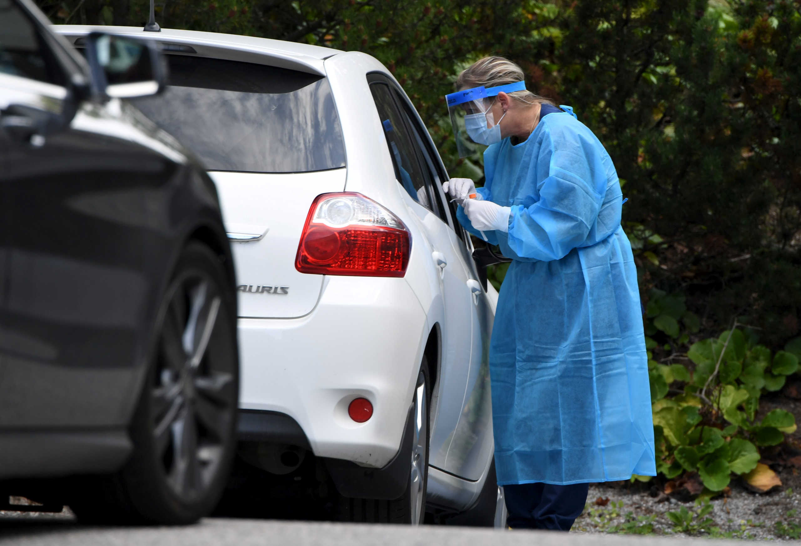 A medical worker wearing a protective suit and a mask takes a swab sample for a coronavirus disease (COVID-19) test at a drive-through testing station in Salo, Finland August 18, 2020.  Lehtikuva