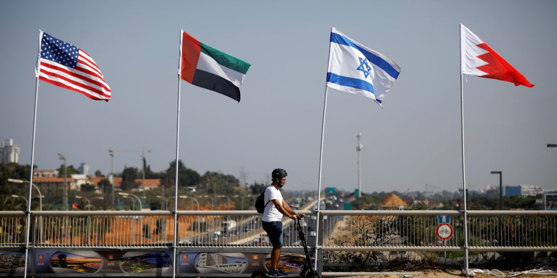 FILE PHOTO: A man rides a scooter near the flags of the U.S., United Arab Emirates, Israel and Bahrain as they flutter along a road in Netanya, Israel September 14, 2020. REUTERS