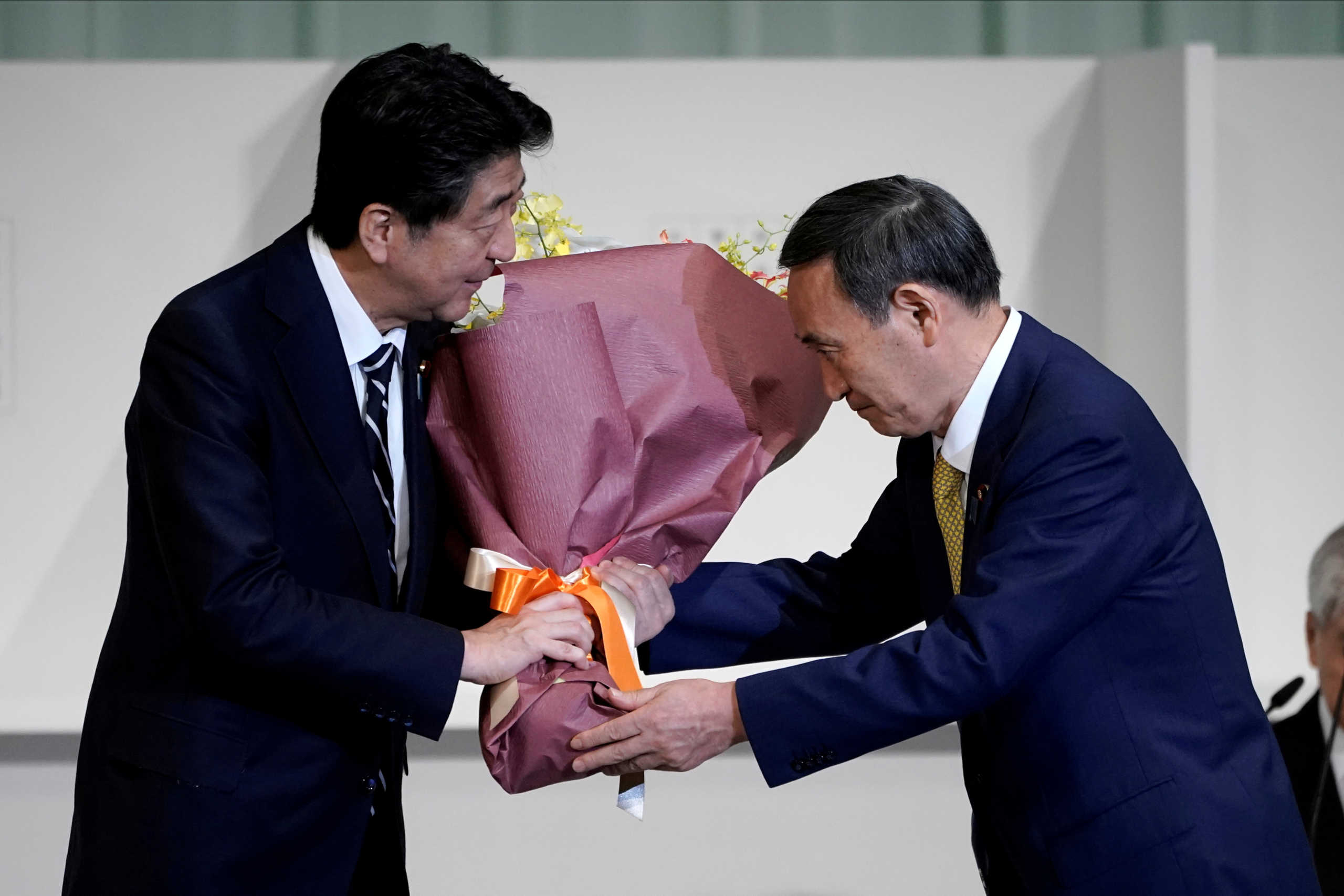 Japan's Chief Cabinet Secretary Yoshihide Suga presents Prime Minister Shinzo Abe with flowers after Suga was elected as new head of the ruling party at the Liberal Democratic Party's (LDP) leadership election in Tokyo, Japan September 14, 2020. Eugene Hoshiko