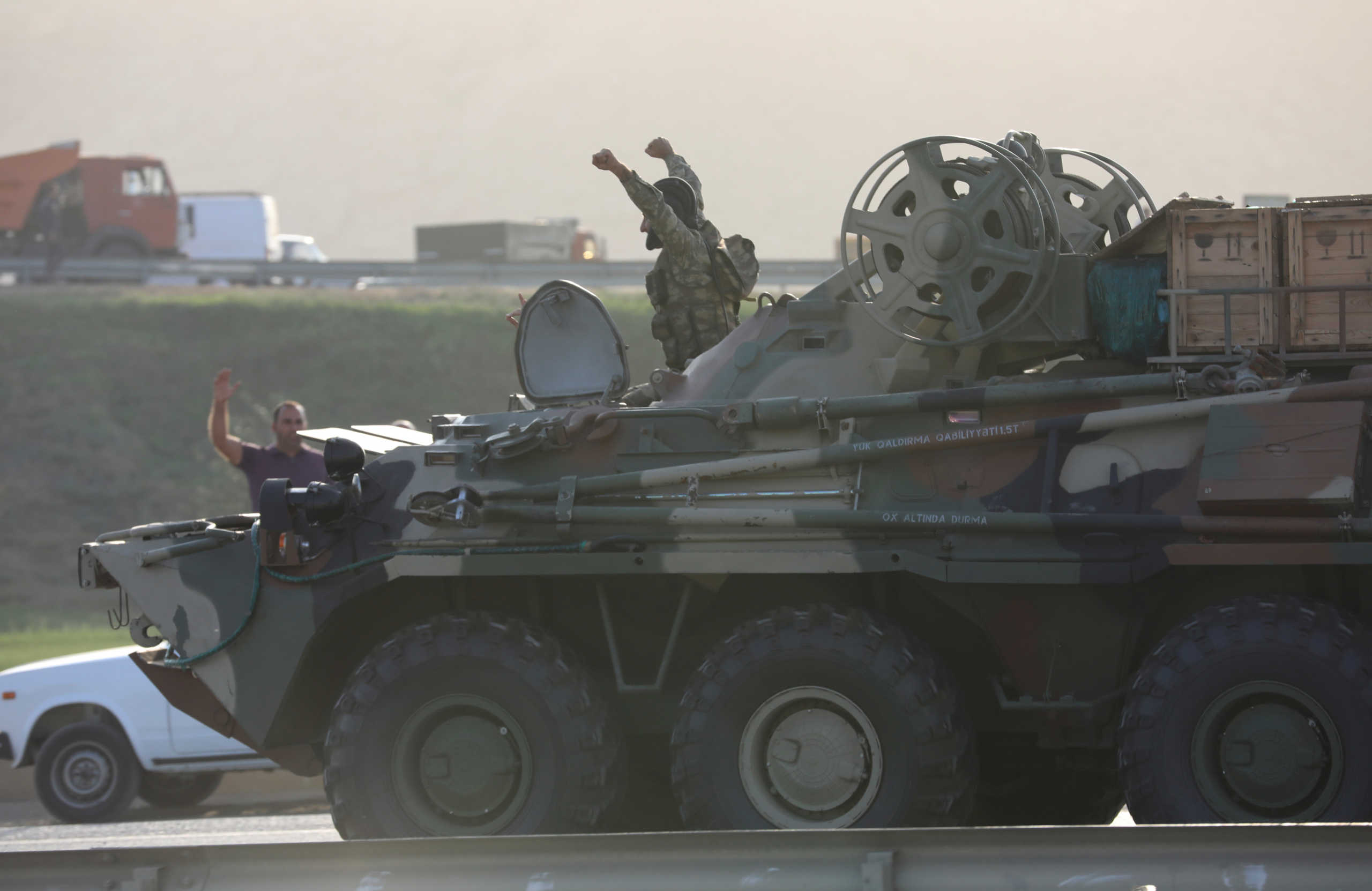 An Azerbaijani service member drives an armoured carrier and greets people, who gather on the roadside in Baku, Azerbaijan September 27, 2020. REUTERS