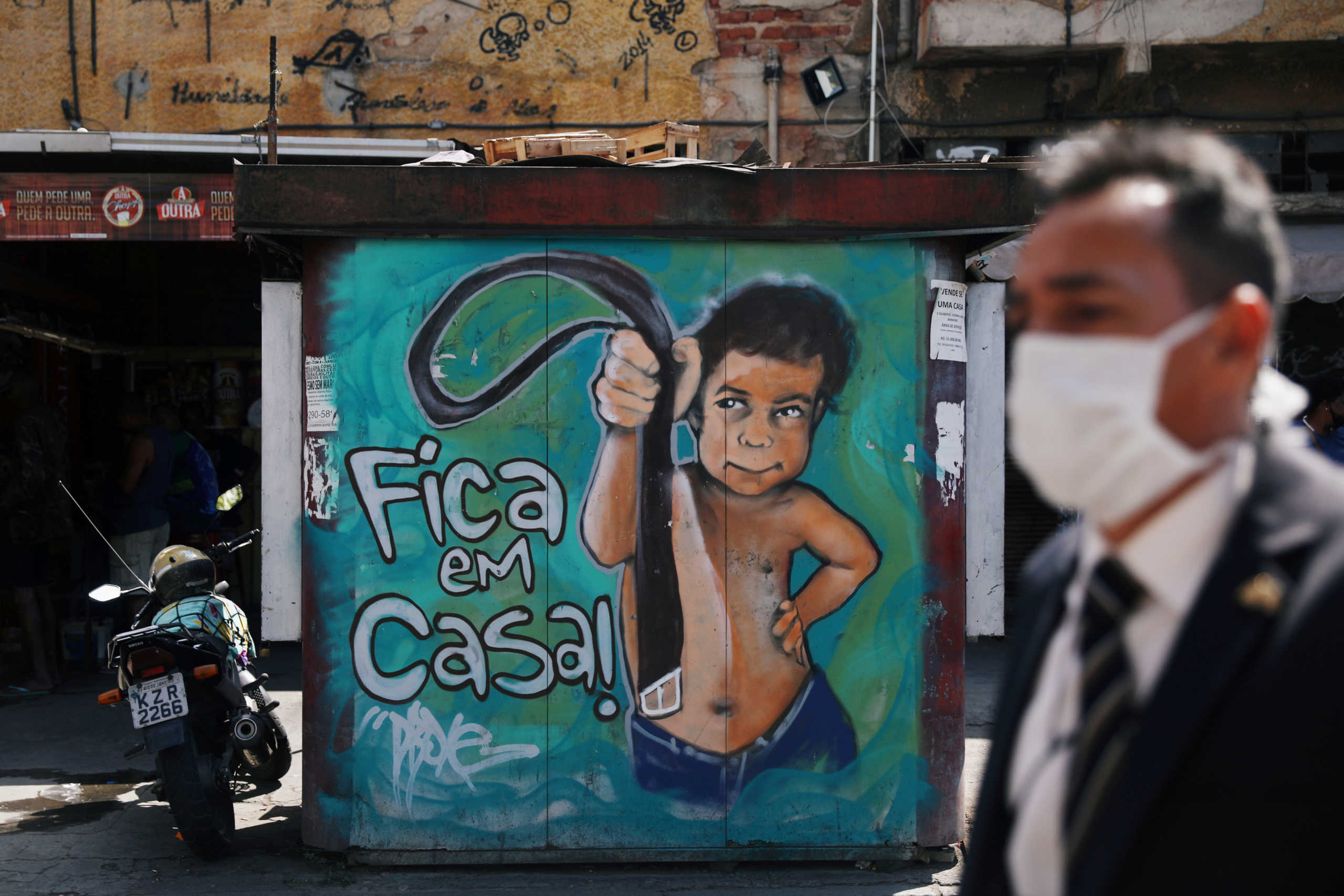 FILE PHOTO: A man wearing a protective mask walks past a graffiti reading "Stay at Home", following the coronavirus disease (COVID-19) outbreak, in Rio de Janeiro, Brazil September 2, 2020. REUTERS