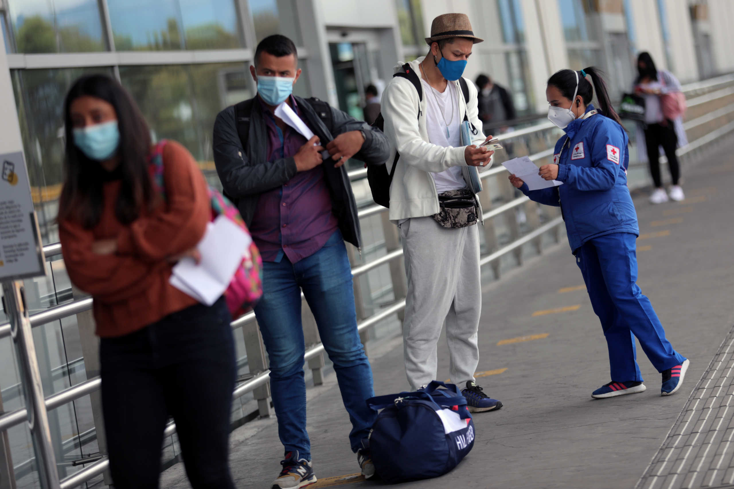 A Red Cross employee wearing a face mask talks to a passenger, after the Colombian government gave authorization to reactivate international flights, amidst the coronavirus disease (COVID-19) outbreak, in Bogota, Colombia September 21, 2020. REUTERS