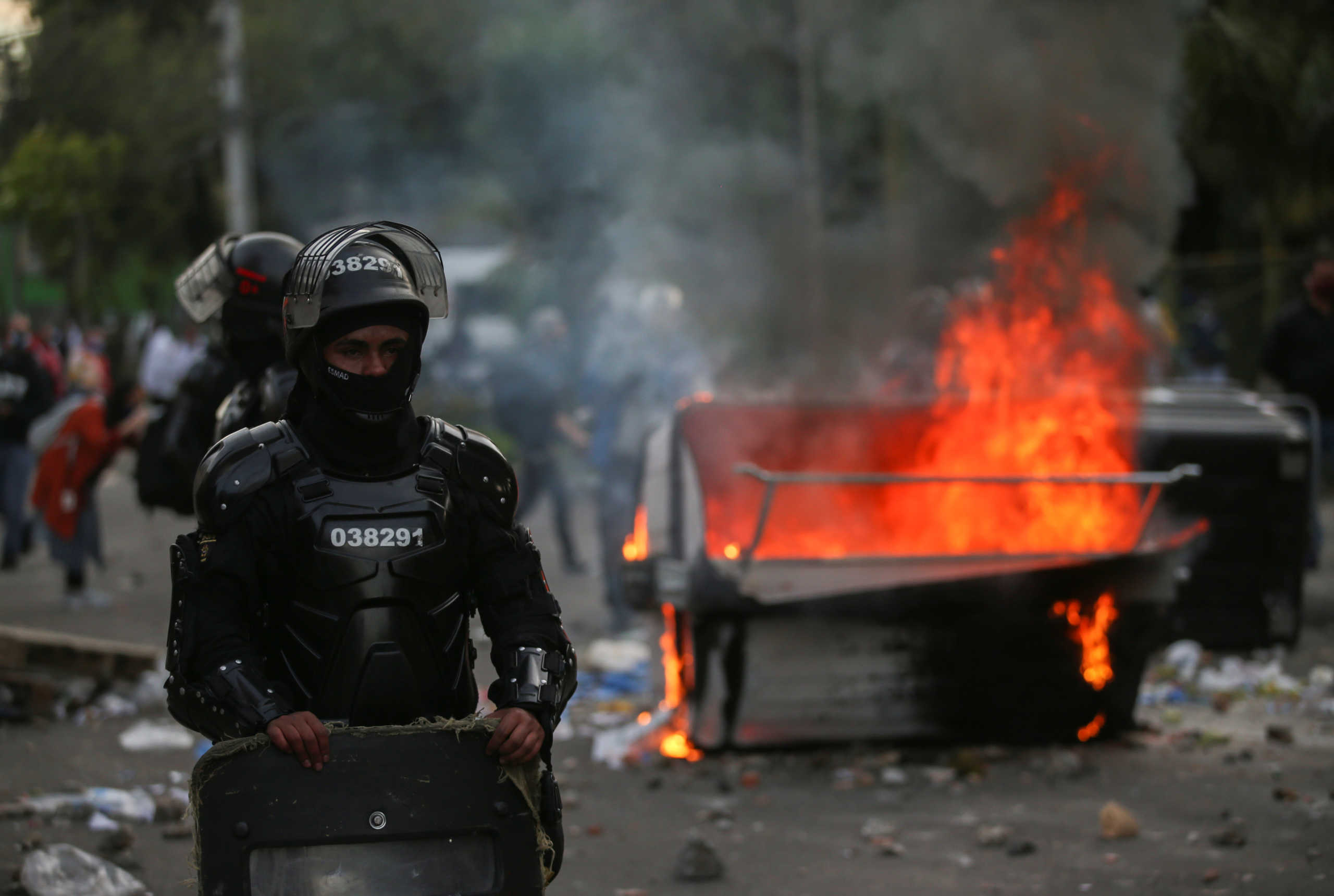 Riot police stand next to a burning garbage container during clashes with protesters after a man, who was detained for violating social distancing rules, died from being repeatedly shocked with a stun gun by officers, according to authorities, in Bogota, Colombia September 9, 2020. REUTERS