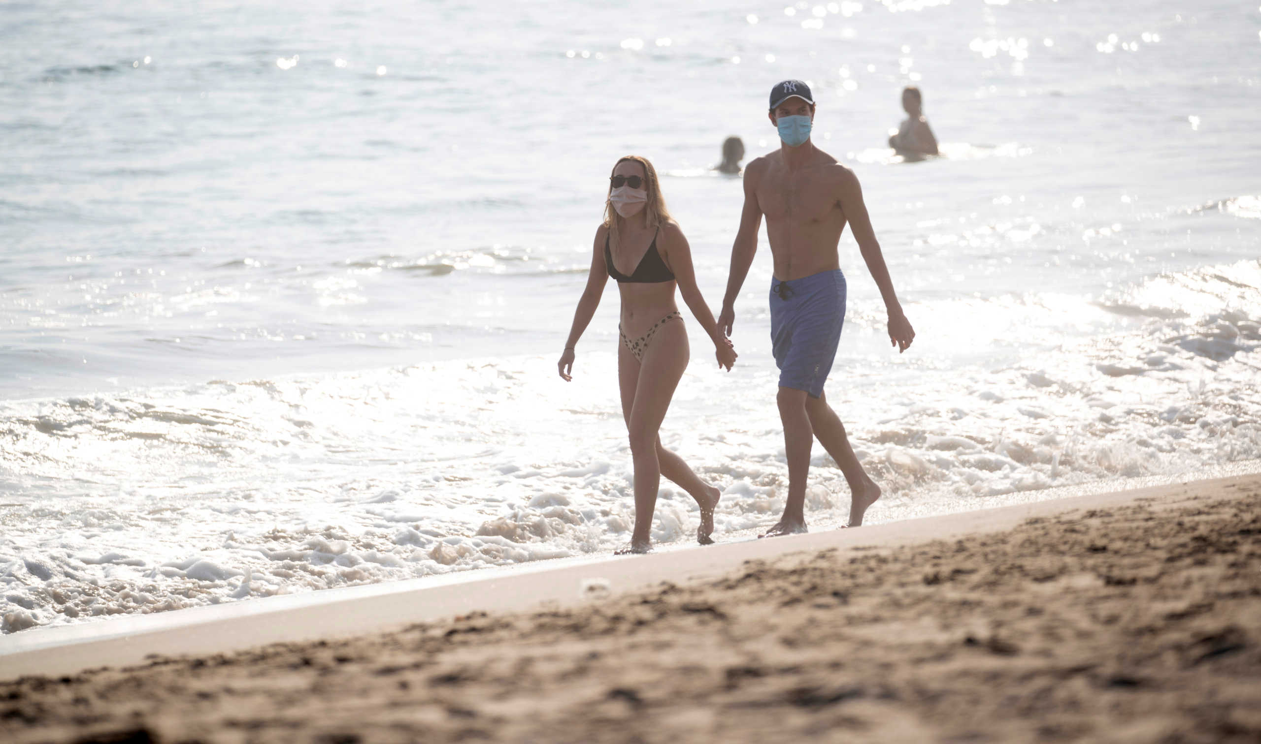 A couple wearing face masks walks on the beach during a heat wave during the outbreak of the coronavirus disease (COVID-19), in Pacific Palisades, California, U.S., August 19, 2020. REUTERS