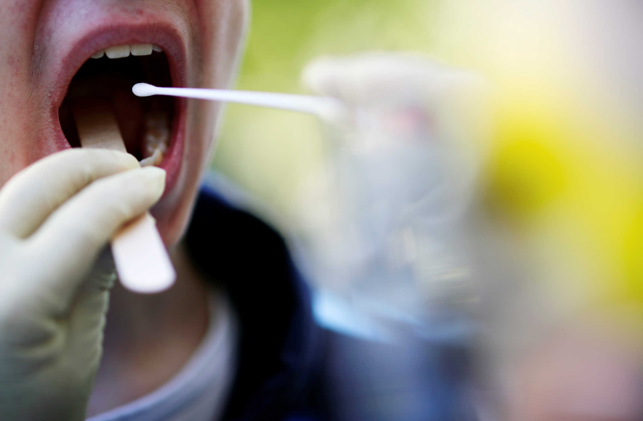 A paediatrician wearing a protective suit takes a swab sample from a young boy for a coronavirus disease (COVID-19) test in front of his medical office in Berlin, Germany September 22, 2020. REUTERS