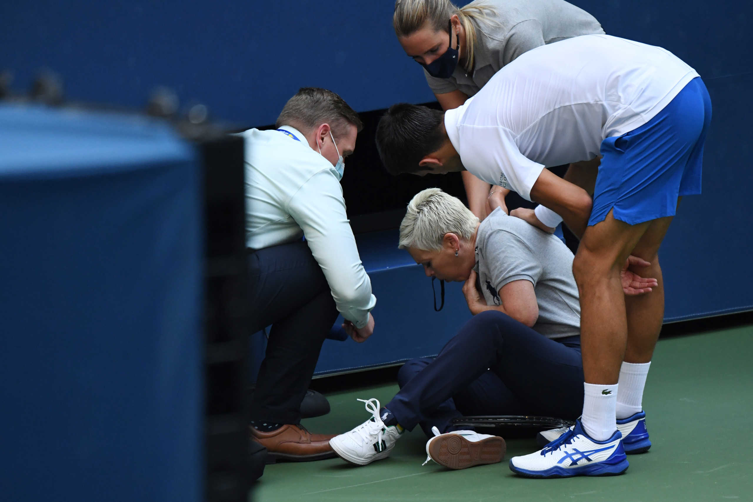 Sep 6, 2020; Flushing Meadows, New York, USA; Novak Djokovic of Serbia and a tournament official tend to a linesperson who was struck with a ball by Djokovic against Pablo Carreno Busta of Spain (not pictured) on day seven of the 2020 U.S. Open tennis tournament at USTA Billie Jean King National Tennis Center. Mandatory Credit: Danielle Parhizkaran-USA TODAY Sports