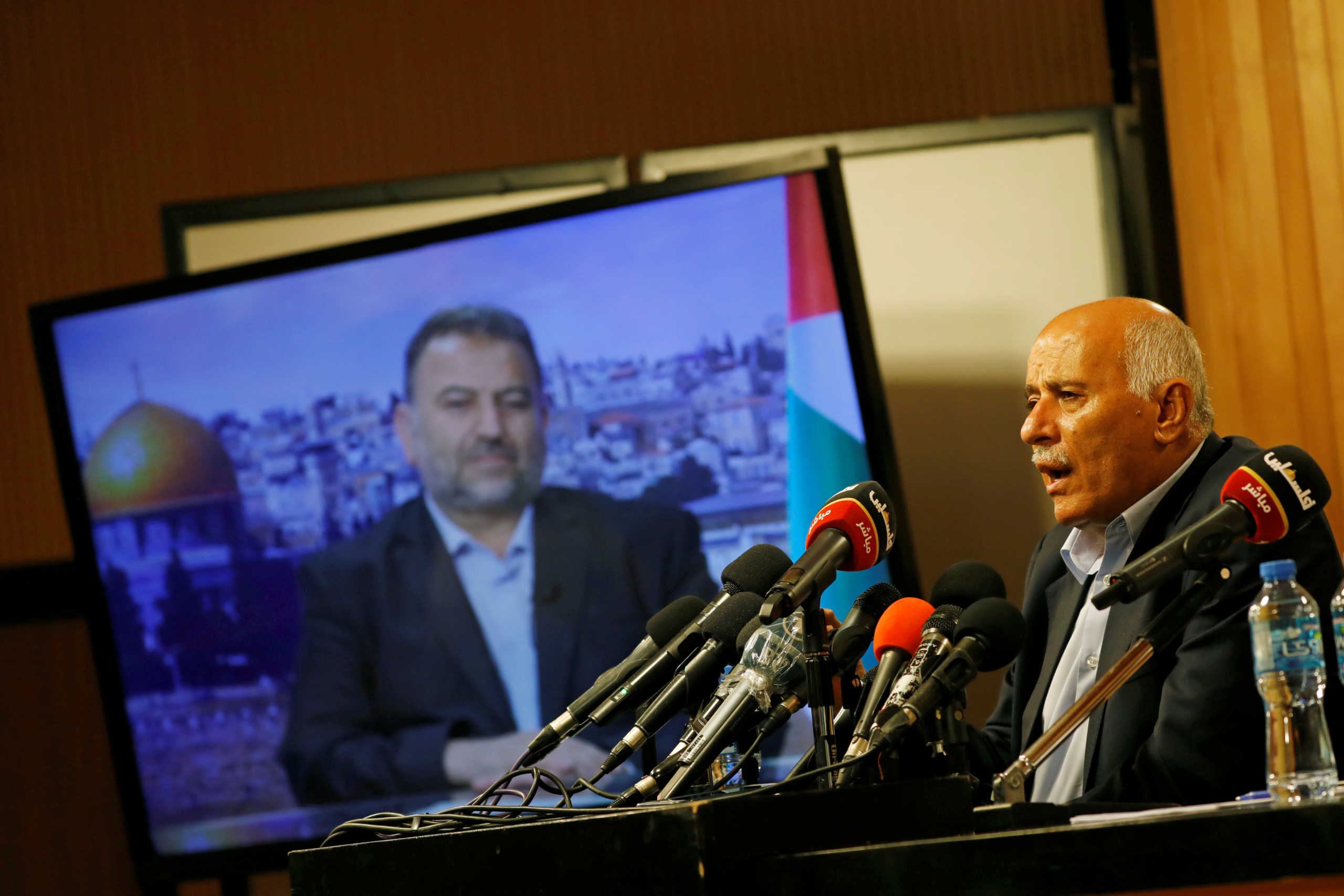 FILE PHOTO: Senior Fatah official Jibril Rajoub speaks as deputy Hamas chief Saleh Arouri appears on a television screen during a video conference to discuss Israel's plan to annex parts of the Israeli-occupied West Bank, in Ramallah July 2, 2020. REUTERS