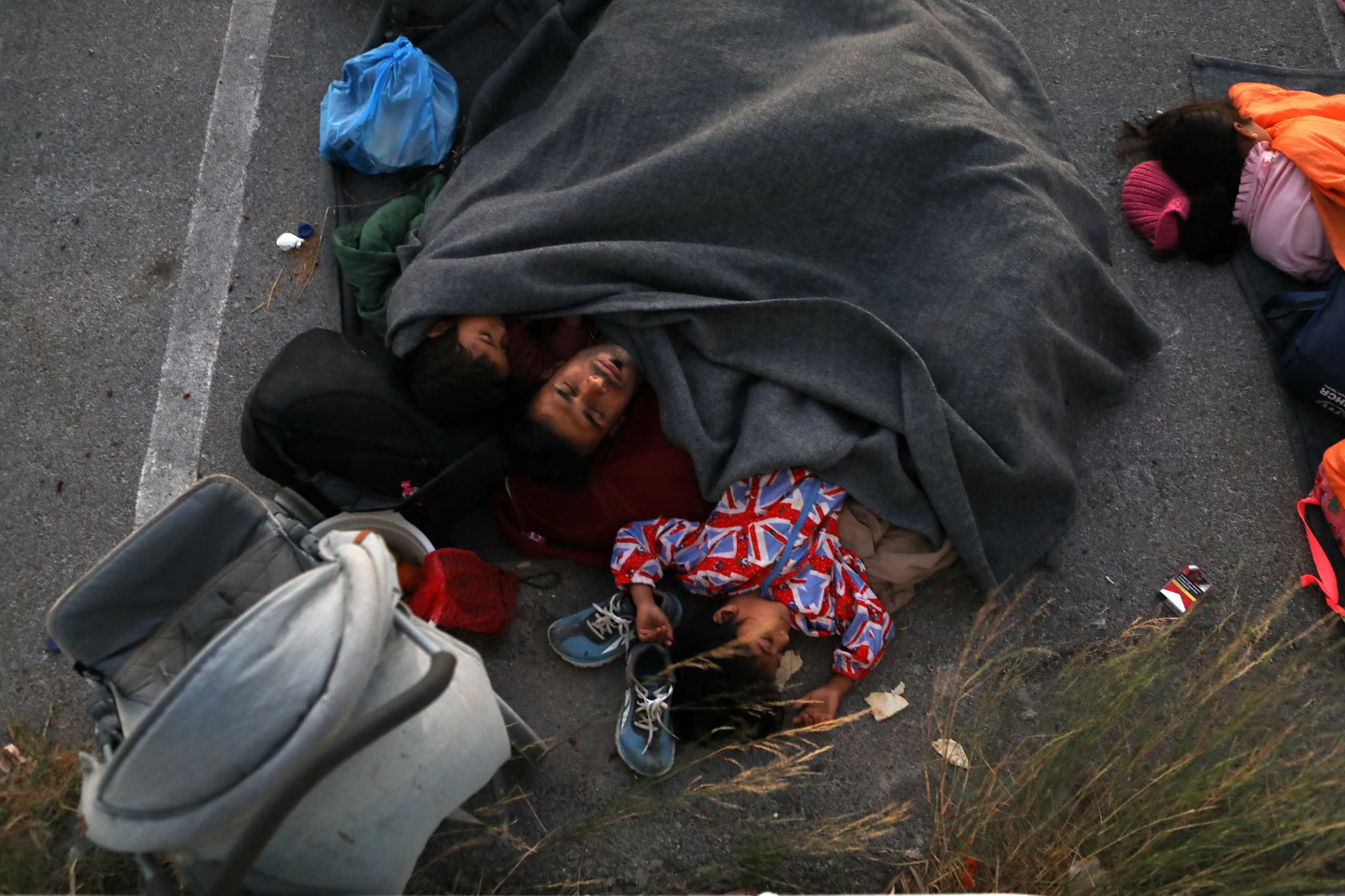 A family sleeps at a parking space, following a fire at the Moria camp for refugees and migrants on the island of Lesbos, Greece, September 9, 2020. REUTERS