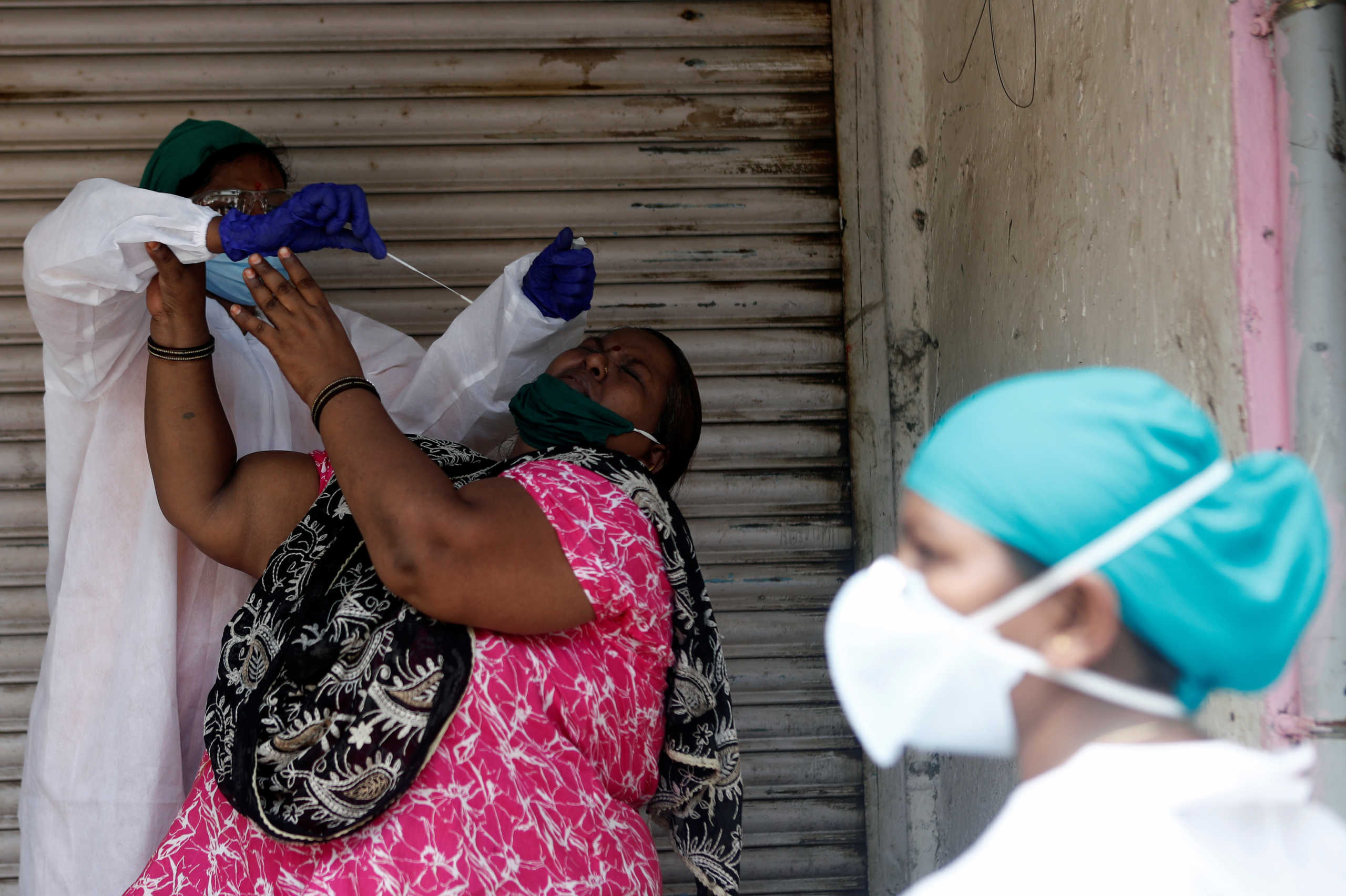 A woman reacts as a health worker in personal protective equipment (PPE) takes a swab during a check up campaign for the coronavirus disease (COVID-19) in a slum area in Mumbai, India September 5, 2020. REUTERS