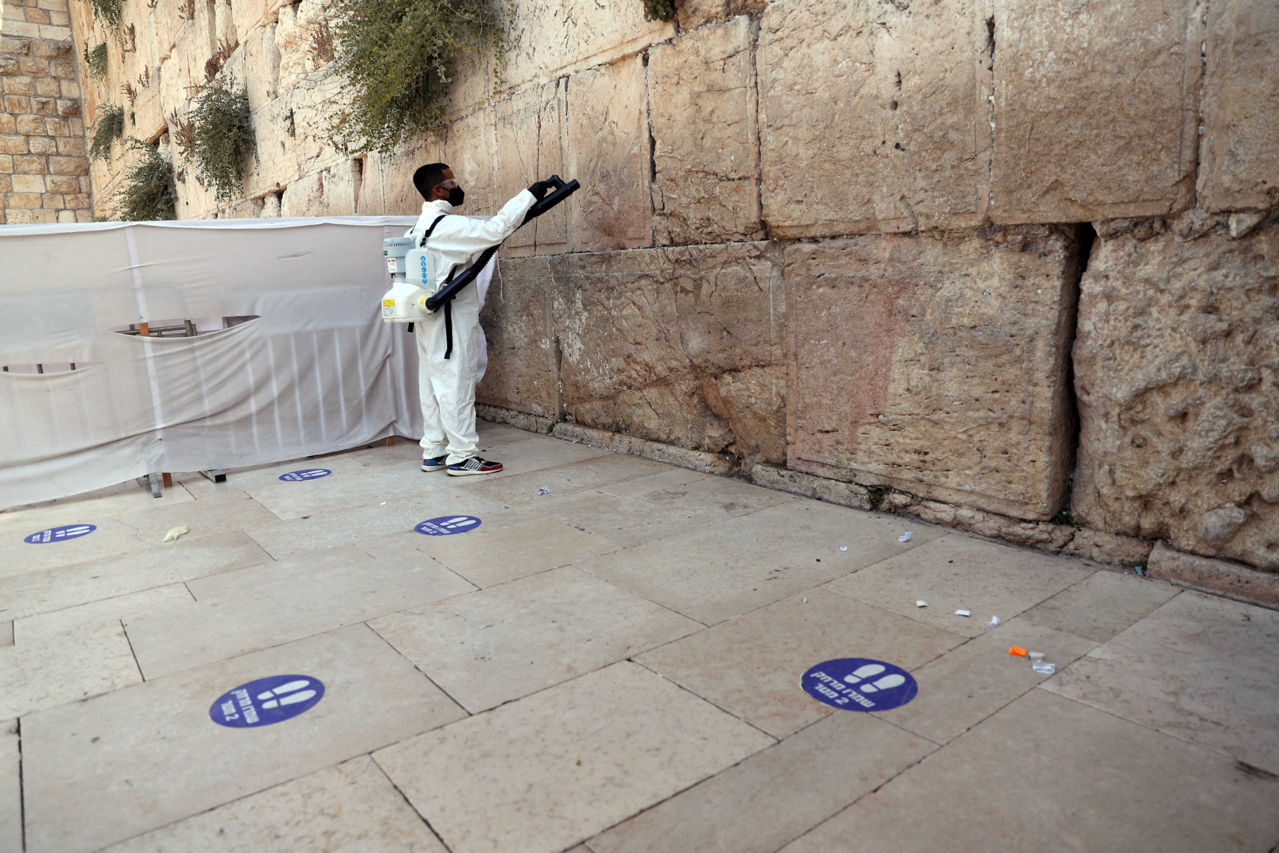 A labourer disinfects and clears out notes left by worshippers in the cracks between the stones of the Western Wall, Judaism's holiest prayer site, ahead of the Jewish New Year, amid the coronavirus disease (COVID-19) crisis, in Jerusalem September 16, 2020. REUTERS