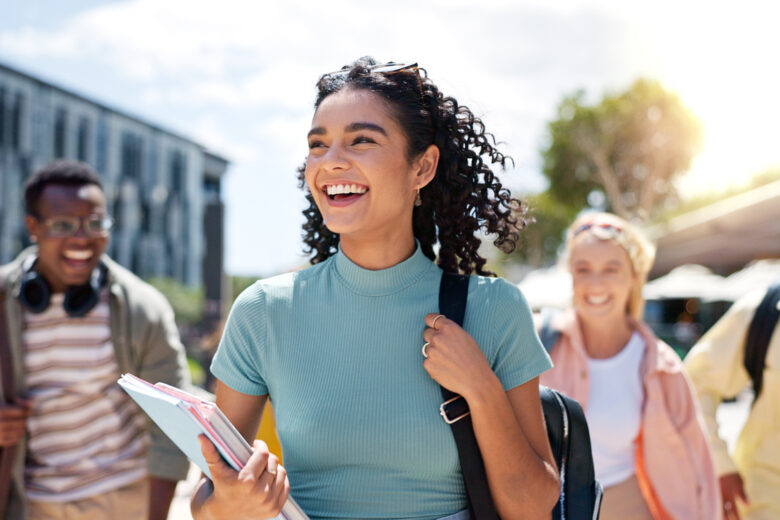 Walking, happy and girl with friends at university for learning, bonding and talking with fun. People, school and group of gen z students commuting outdoor ready for education at college campus.