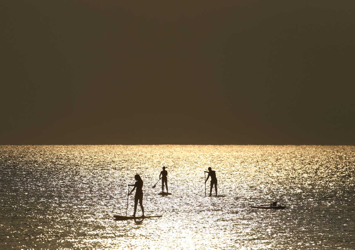 People paddle on a stand-up board during sunrise near a beach in Larnaca, Cyprus August 27, 2020. REUTERS