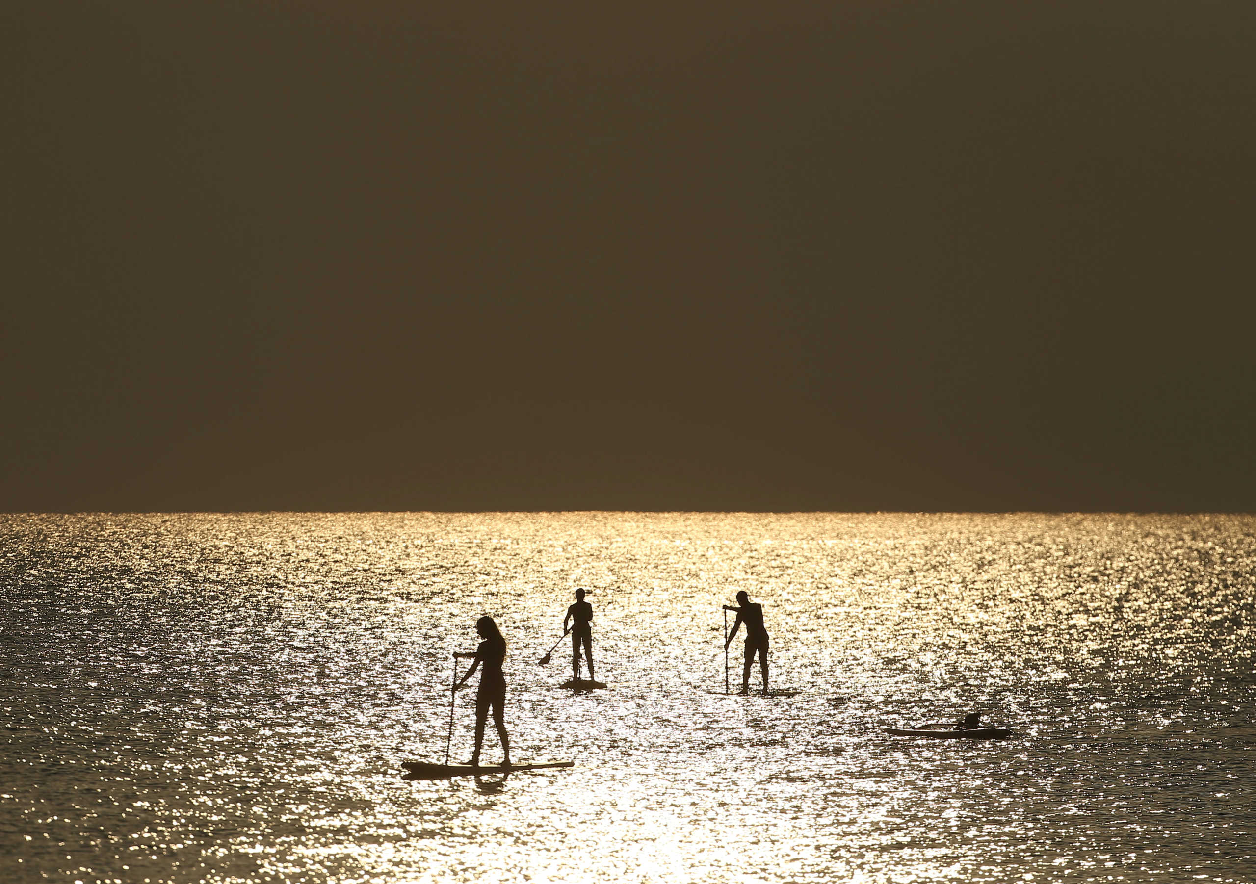 People paddle on a stand-up board during sunrise near a beach in Larnaca, Cyprus August 27, 2020. REUTERS