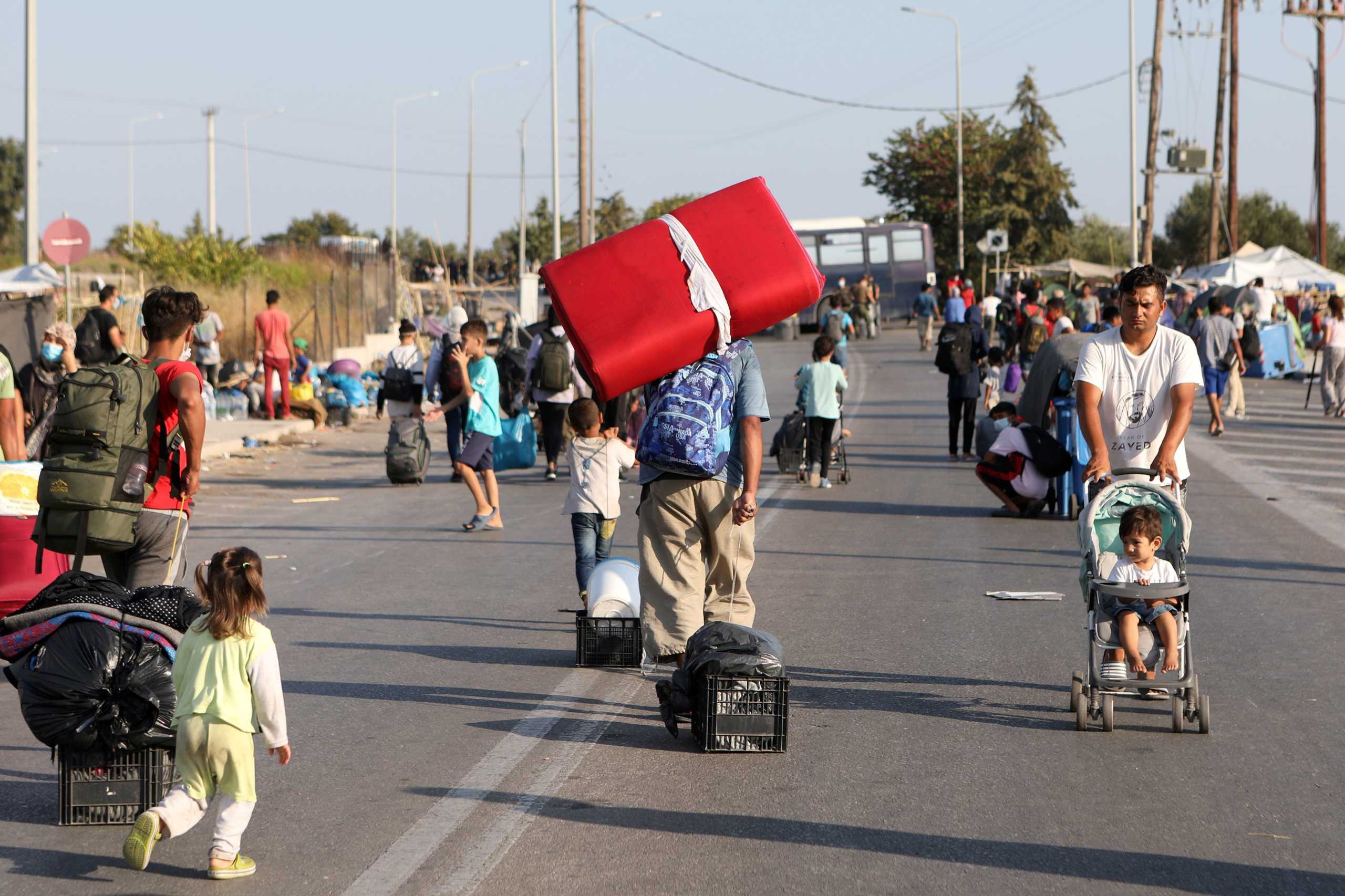 Refugees and migrants from the destroyed Moria camp move towards a new temporary camp during a police operation, on the island of Lesbos, Greece, September 17, 2020. REUTERS