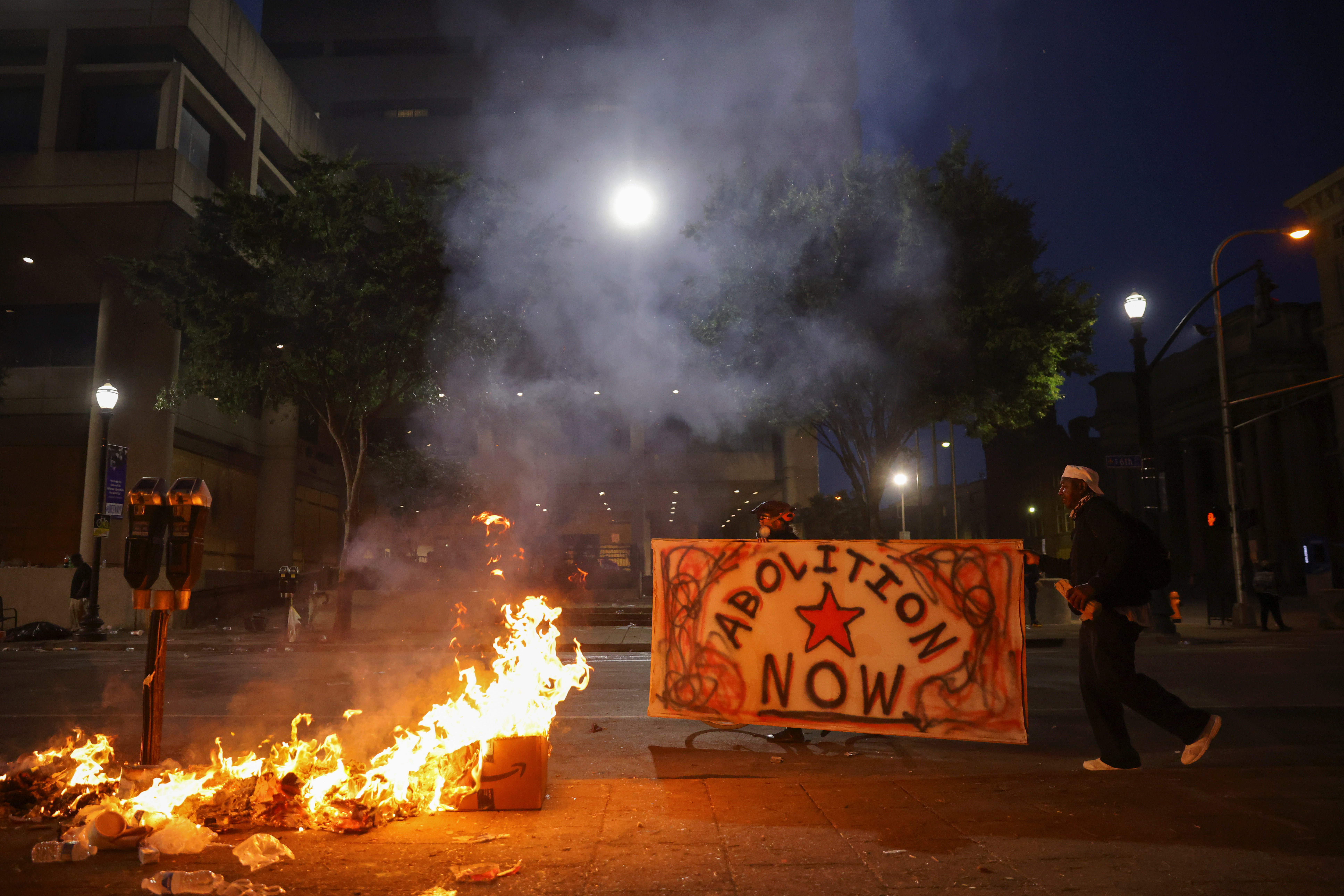 Protesters carry a sign as they walk by a fire in front of the Louis D. Brandeis Hall of Justice after a grand jury voted to indict one of three white police officers for wanton endangerment in the death of Breonna Taylor, who was shot dead by police in her apartment, in Louisville, Kentucky, U.S. September 23, 2020. REUTERS