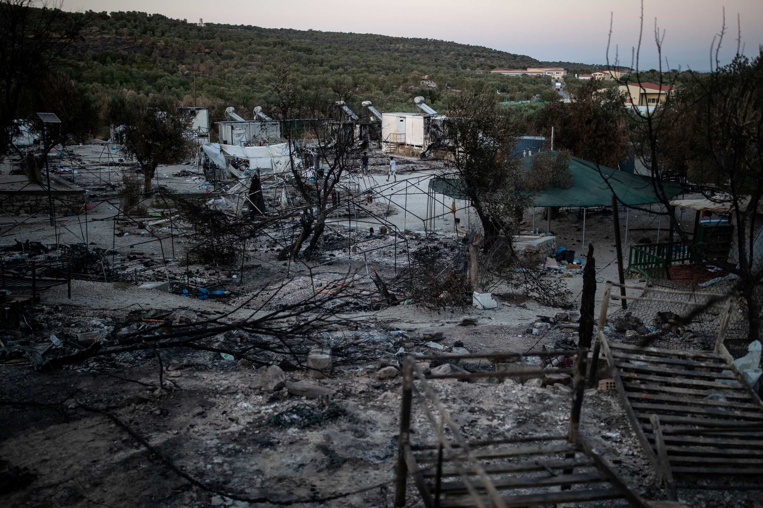FILE PHOTO: Men make their way at the destroyed Moria camp for refugees and migrants, on the island of Lesbos, Greece, September 14, 2020. REUTERS