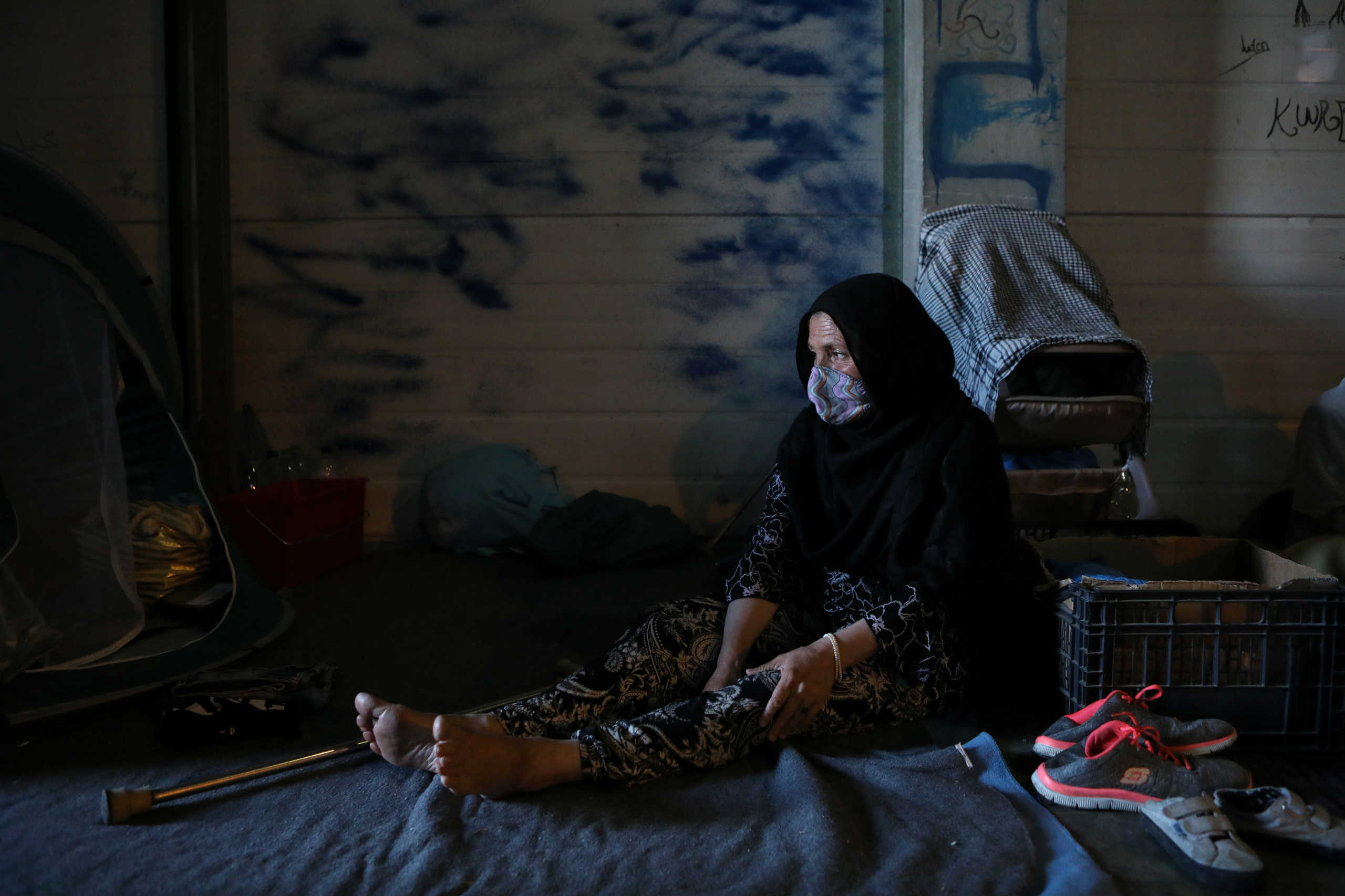 A woman from the destroyed Moria camp rests inside a warehouse where refugees and migrants find shelter near a new temporary camp, on the island of Lesbos, Greece, September 14, 2020. REUTERS