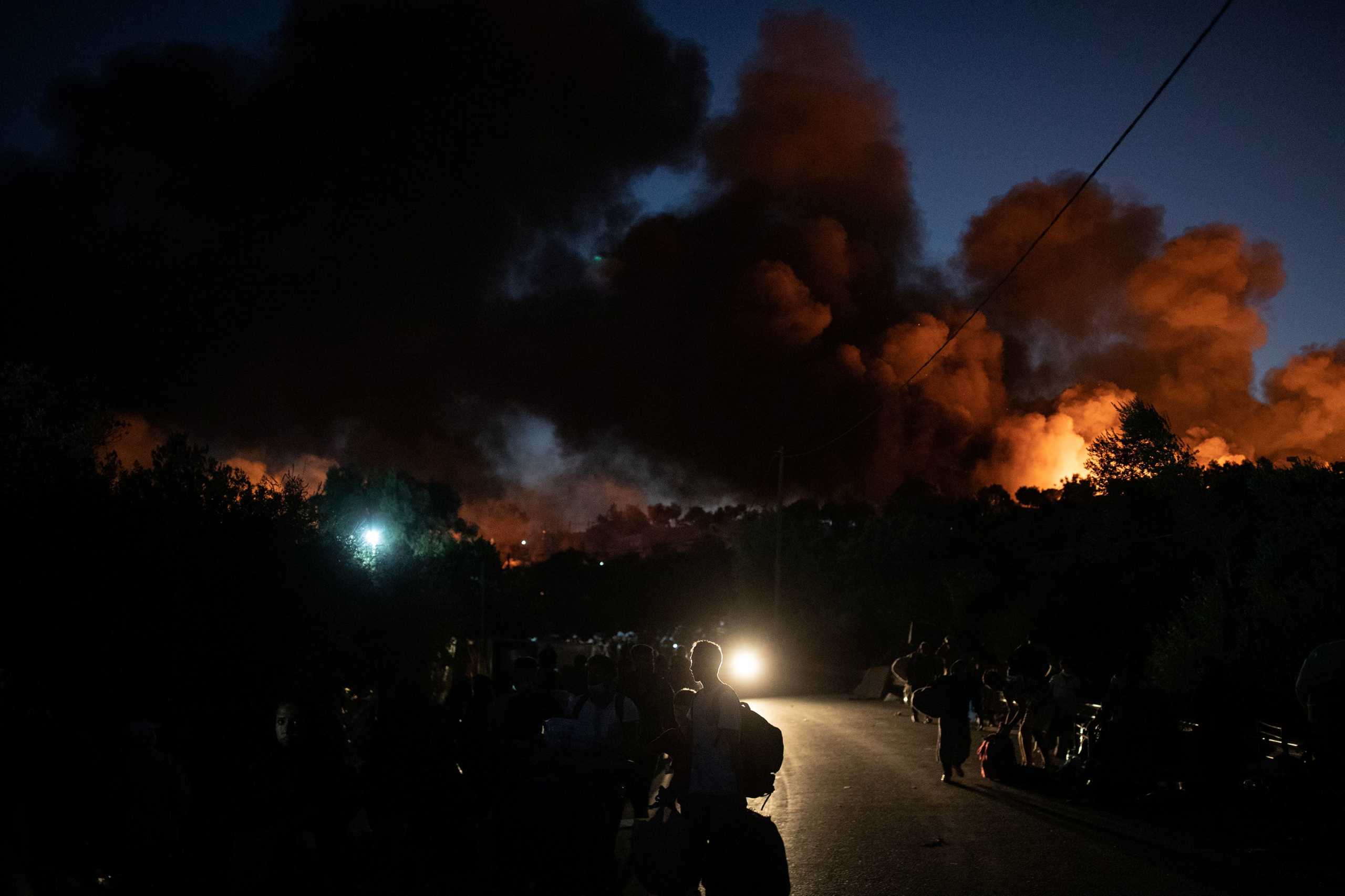 Refugees and migrants carrying their belongings flee a fire burning at the Moria camp on the island of Lesbos, Greece, September 9, 2020. REUTERS