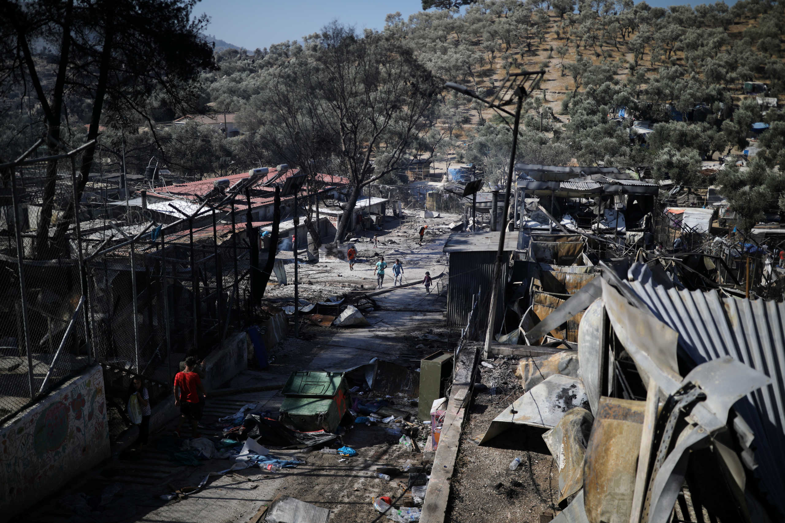 Refugees and migrants walk among destroyed shelters following a fire at the Moria camp on the Island of Lesbos, Greece September 9, 2020. REUTERS