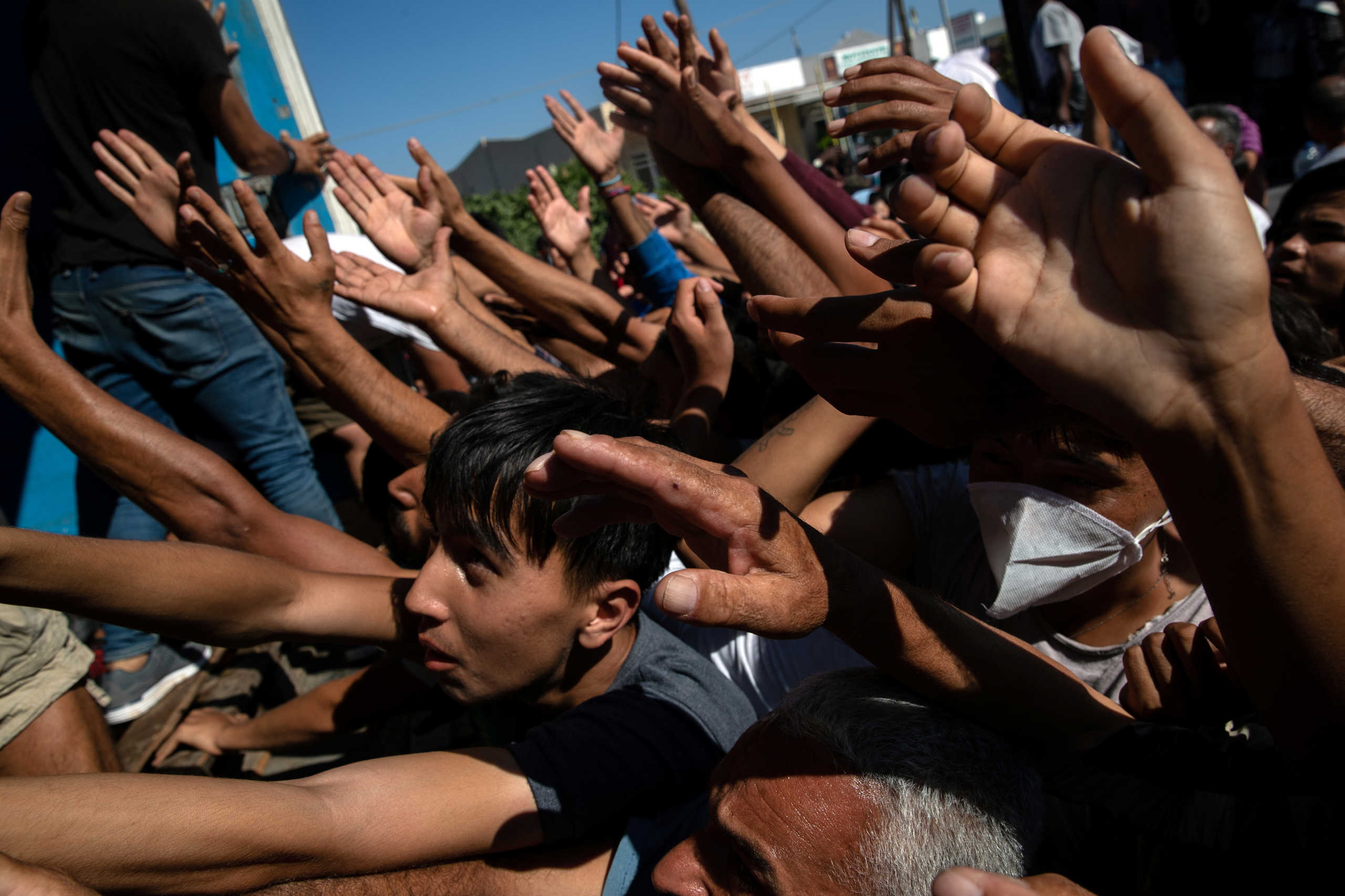 Refugees and migrants are handed tomatoes during a food distribution following a fire at the Moria camp on the island of Lesbos, Greece, September 10, 2020. REUTERS