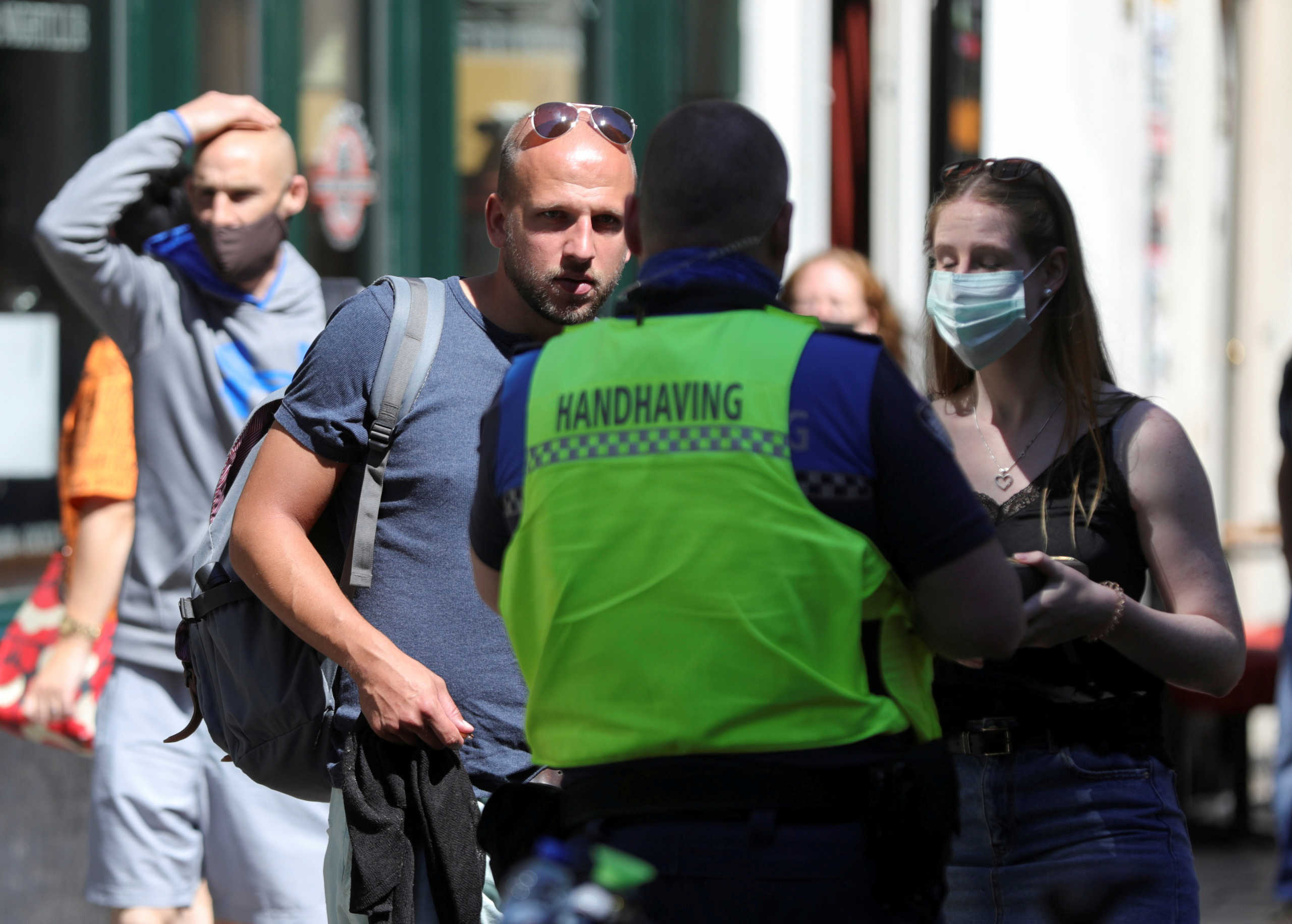 FILE PHOTO: An enforcement officer instructs people to wear the mandatory masks at the Red Light District, during the coronavirus disease (COVID-19) outbreak, in Amsterdam, Netherlands August 5, 2020. REUTERS