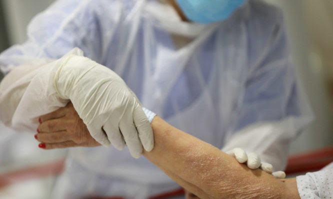 FILE PHOTO: A healthcare worker treats an elderly patient at the emergency room as the spread of the coronavirus disease (COVID-19) continues, at Infanta Sofia University hospital in Madrid, Spain, May 8, 2020. REUTERS