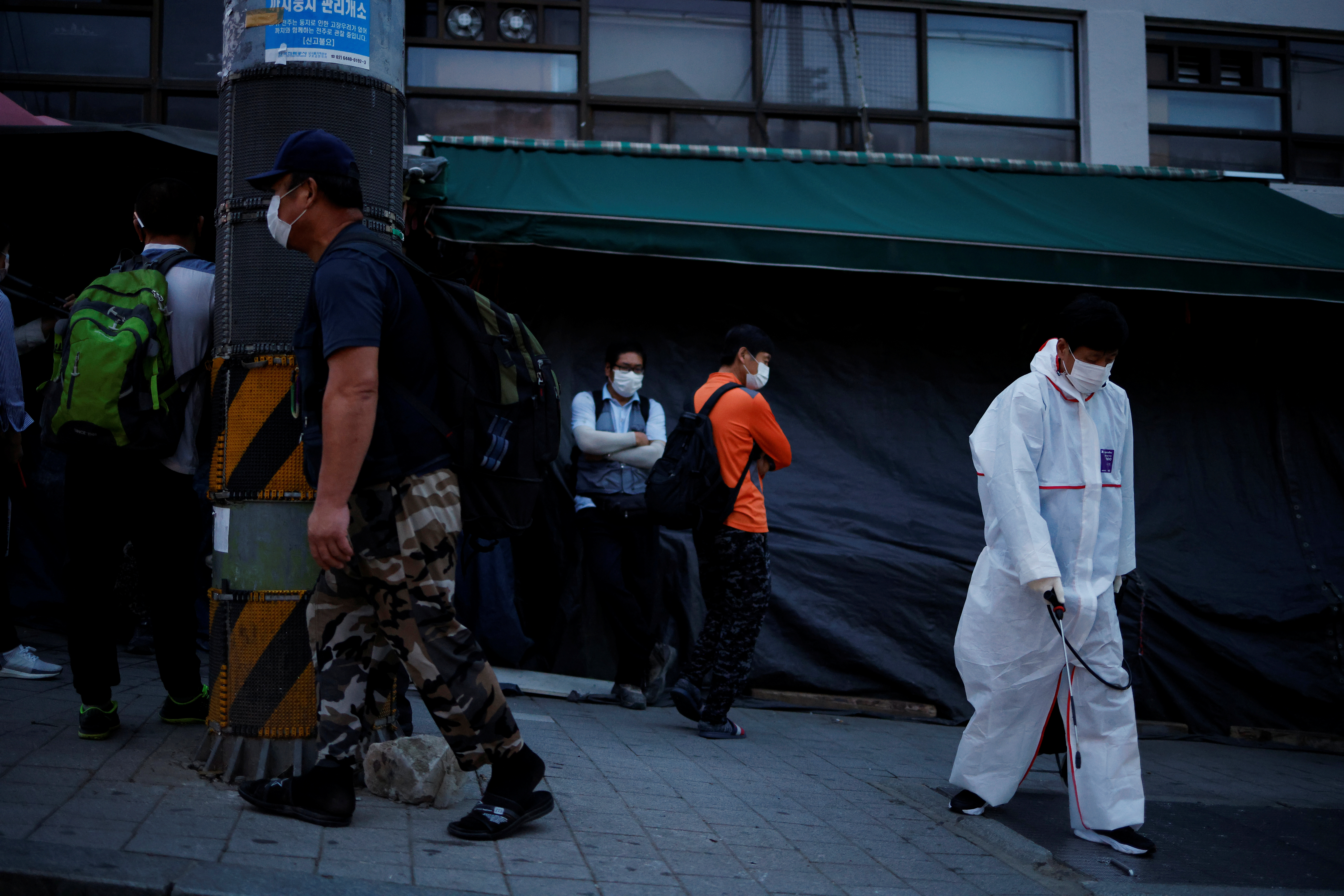 A government official sanitizes a street as day workers gather to seek a job amid the coronavirus disease (COVID-19) pandemic in Seoul, South Korea, September 17, 2020.   REUTERS.Kim Hong-Ji
