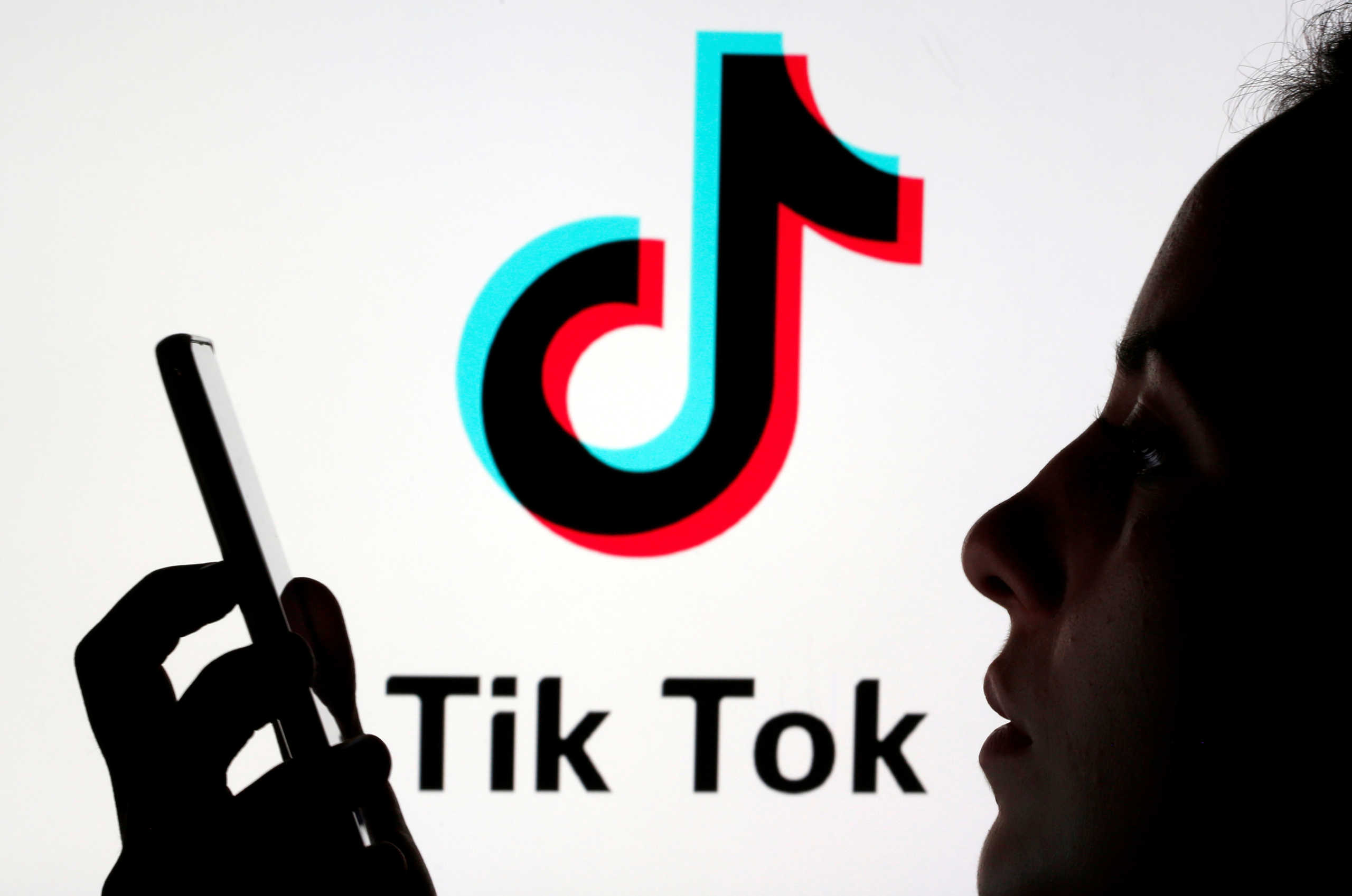 FILE PHOTO: A person holds a smartphone as TikTok logo is displayed behind in this picture illustration taken Nov. 7, 2019. REUTERS