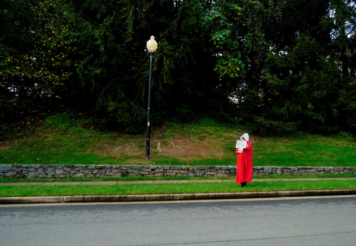 U.S. President Donald Trump is greeted by a woman dressed as a hand maiden from The Handmaid's Tale as he enters the Trump National Golf Club in Sterling, VA., U.S. September 27, 2020. REUTERS