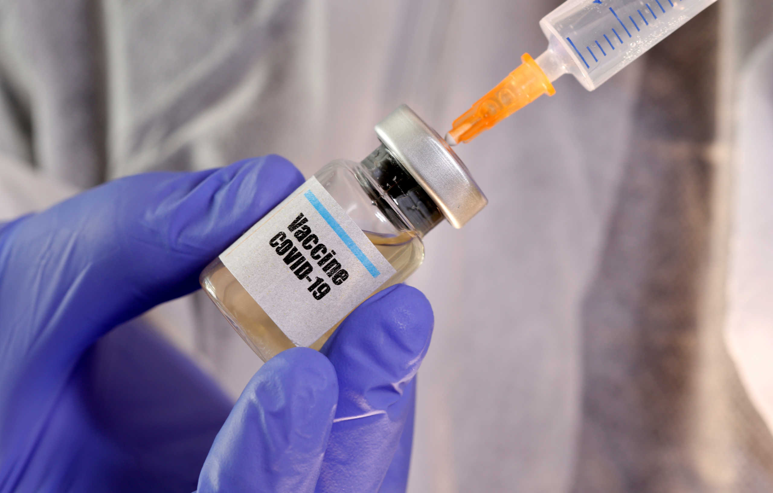 FILE PHOTO: A woman holds a small bottle labeled with a "Vaccine COVID-19" sticker and a medical syringe in this illustration taken April 10, 2020. REUTERS