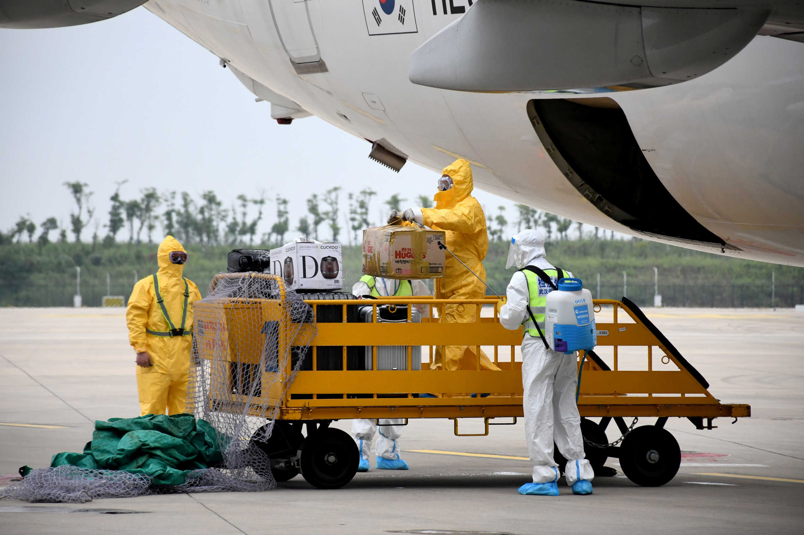 Workers in protective suits disinfect luggage arriving from South Korea via a flight by South Korea's budget carrier T'way Air, the first international carrier that flies to Wuhan after months of flight suspension due to the coronavirus disease (COVID-19) outbreak, at Wuhan Tianhe International Airport in Wuhan, Hubei province, China September 16, 2020. Picture taken September 16, 2020. cnsphoto via REUTERS   ATTENTION EDITORS - THIS IMAGE WAS PROVIDED BY A THIRD PARTY. CHINA OUT.