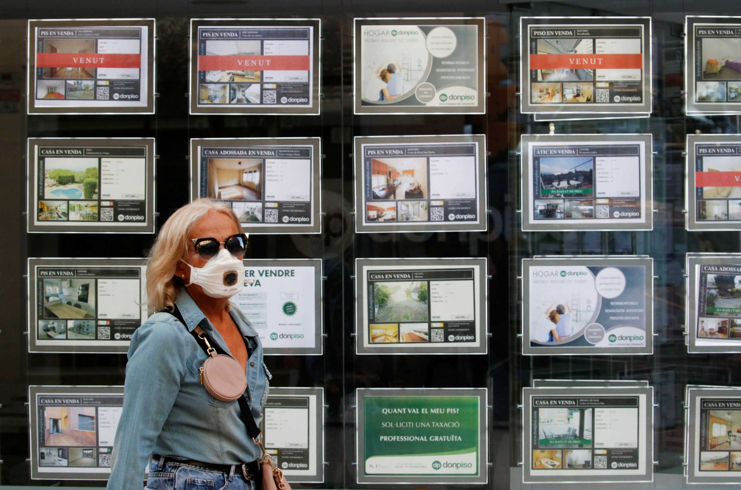 FILE PHOTO: A woman wearing a face mask walks past a Don Piso real estate agency office during the coronavirus disease (COVID-19) outbreak in El Masnou, north to Barcelona, Spain, May 19, 2020. REUTERS