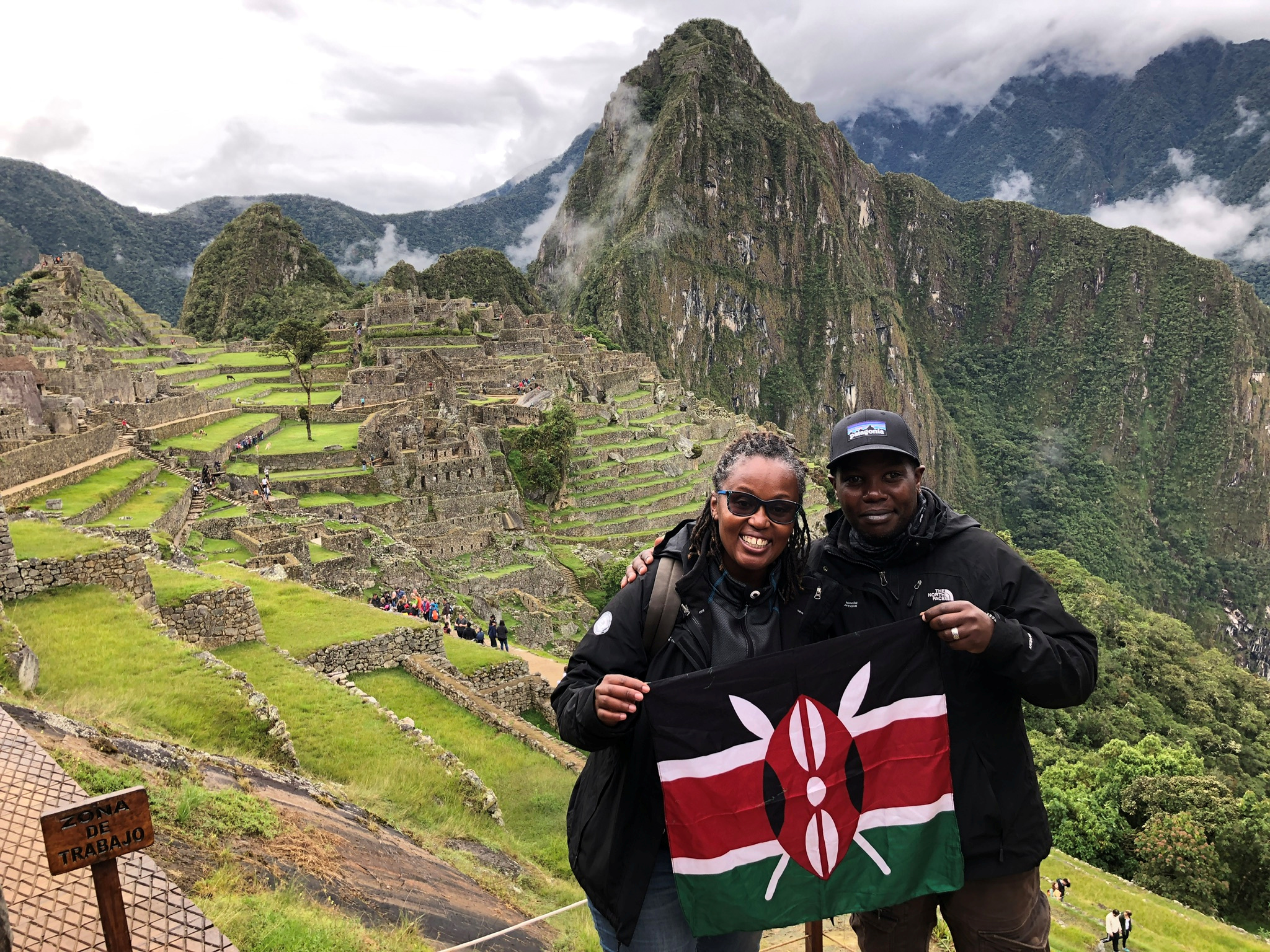 Kenyan biker couple Dos Kariuki and Joanne Wamuyu hold the Kenyan flag as they attempt to travel the world on motorbikes in Machu Picchu, Peru April 16, 2019. Picture taken April 16, 2019. Wamuyu and DoS of Throttle Adventures