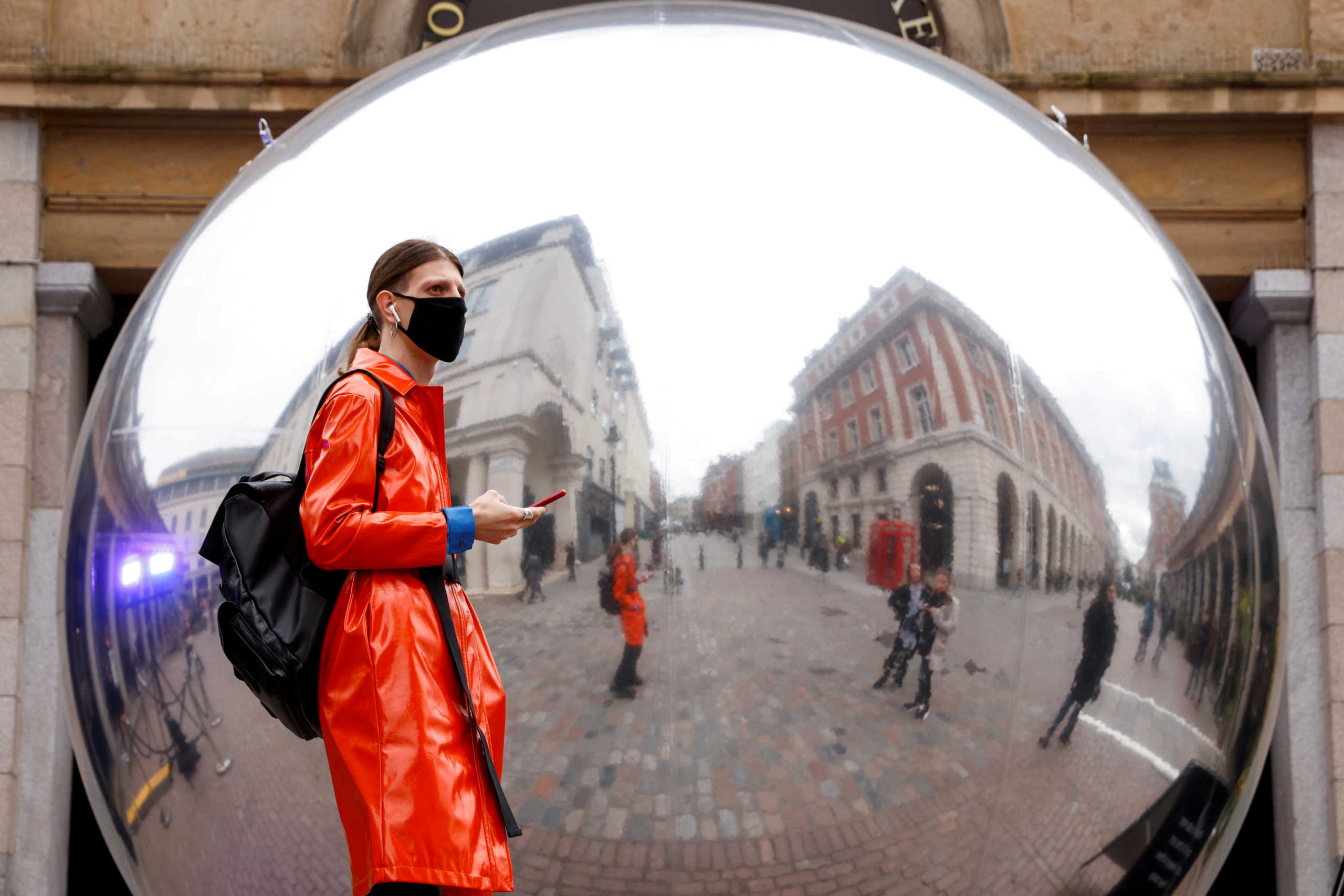 FILE PHOTO: A person wearing a face mask is reflected in an art work entitled "A=V" by Ben Cullen Williams, amid the coronavirus disease (COVID-19) outbreak, in Covent Garden, London, Britain October 16, 2020. REUTERS