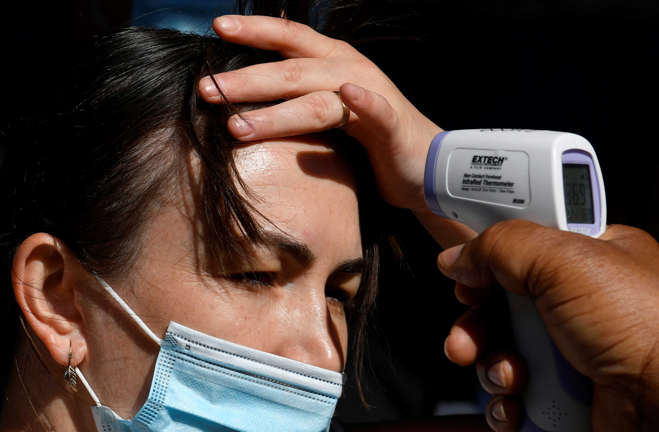 A woman has her temperature taken prior to entering Madame Tussauds waxworks museum on the first day of its reopening since the easing of lockdown amid the spread of the coronavirus disease (COVID-19), in London, Britain, August 1, 2020. REUTERS