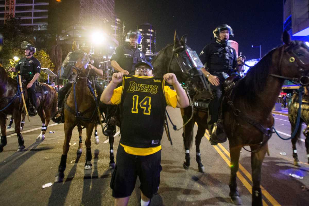 A Lakers fan displays his jersey in front of police as they try to control a crowd on the street outside the Staples Center as fans celebrate their team winning the 2020 NBA Championship against Miami Heat in Los Angeles, California, U.S., October 11, 2020. REUTERS