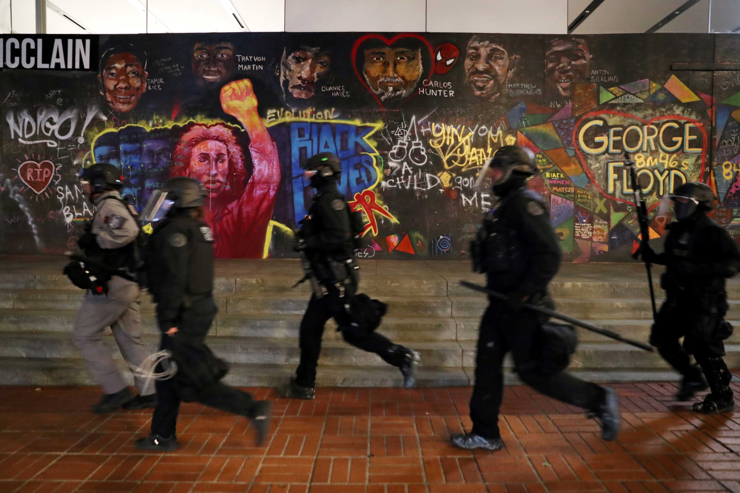 FILE PHOTO: Police officers walk past graffiti during a protest against police violence and racial inequality in Portland, Oregon, U.S., September 27, 2020. REUTERS