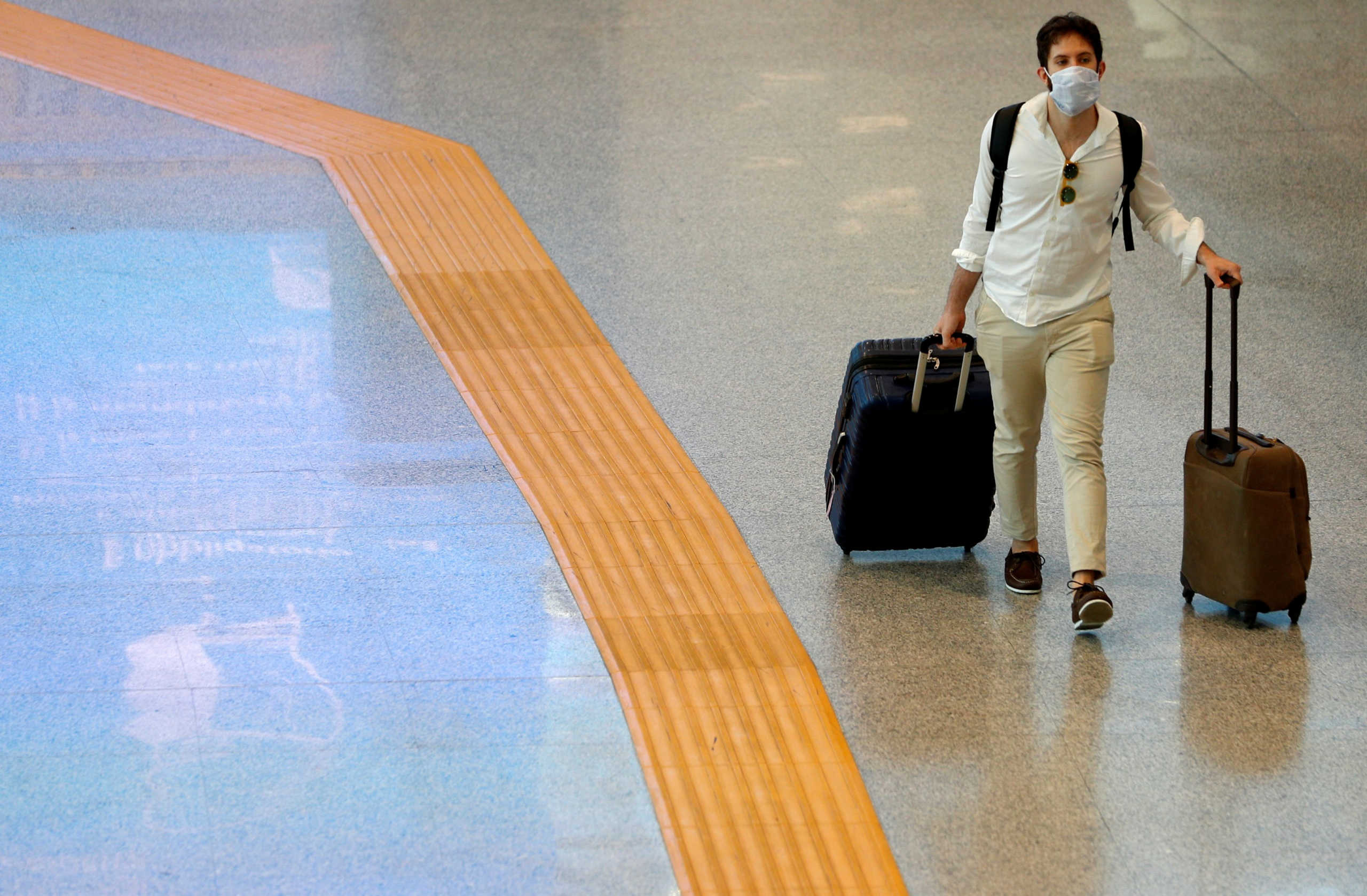 FILE PHOTO: A passenger wearing a protective face mask walks at Fiumicino Airport In Rome, Italy, May 28, 2020. REUTERS