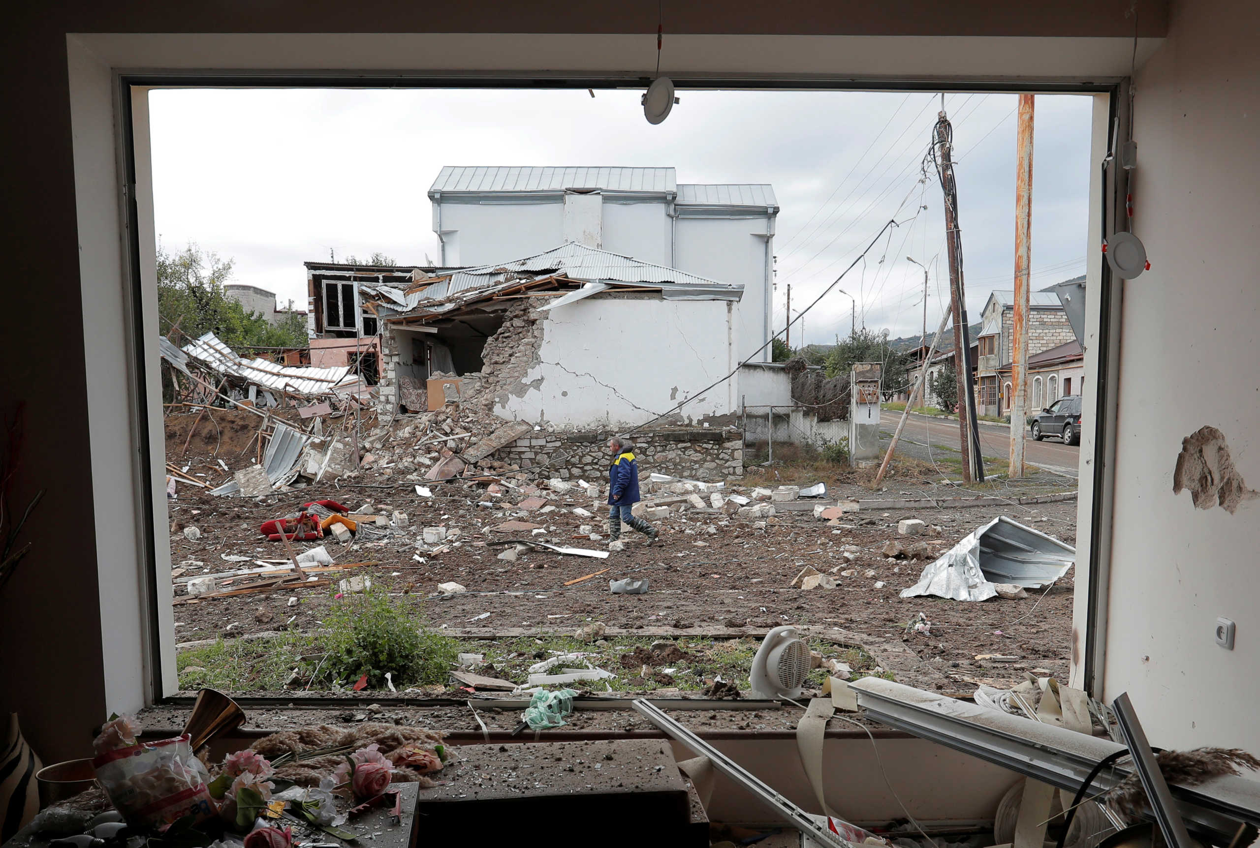 A man walks past a house damaged by recent shelling during the military conflict over the breakaway region of Nagorno-Karabakh, in Stepanakert October 8, 2020. REUTERS