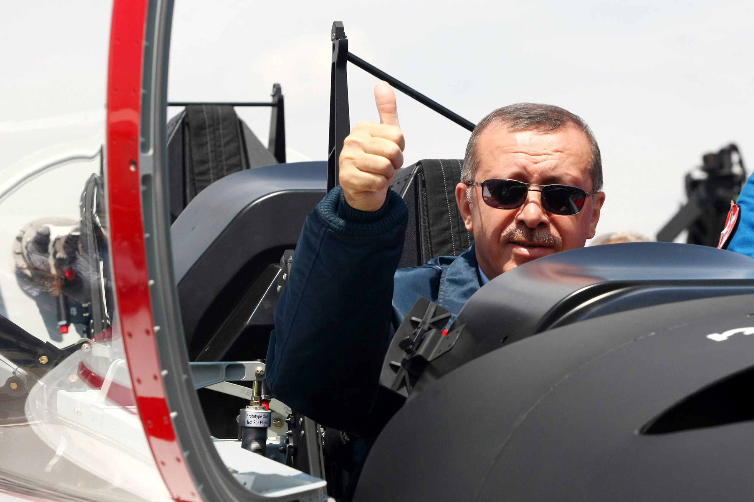 Turkish Prime Minister Recep Tayyip Erdogan gives a thumbs-up sign from the cockpit of the Turkish Primary and Basic Trainer Aircraft "Hurkus" during a ceremony at the Turkish Aerospace Industries in Ankara June 27, 2012.  AFP PHOTO