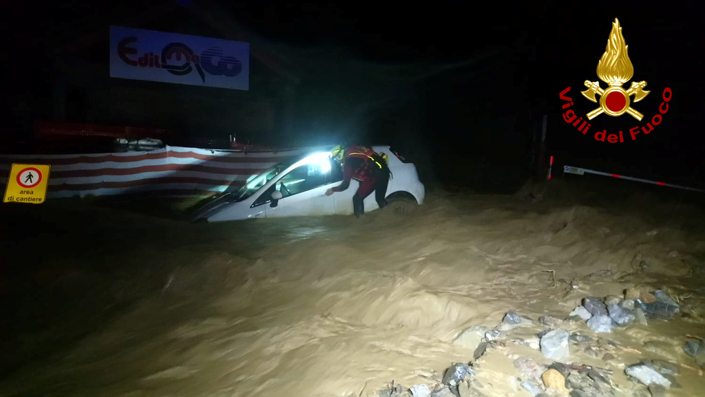 A firefighter is seen next to a partially submerged car after heavy rains caused flooding in the town of Limone Piemonte, Italy, October 2, 2020. Picture taken October 2, 2020. Vigili del Fuoco
