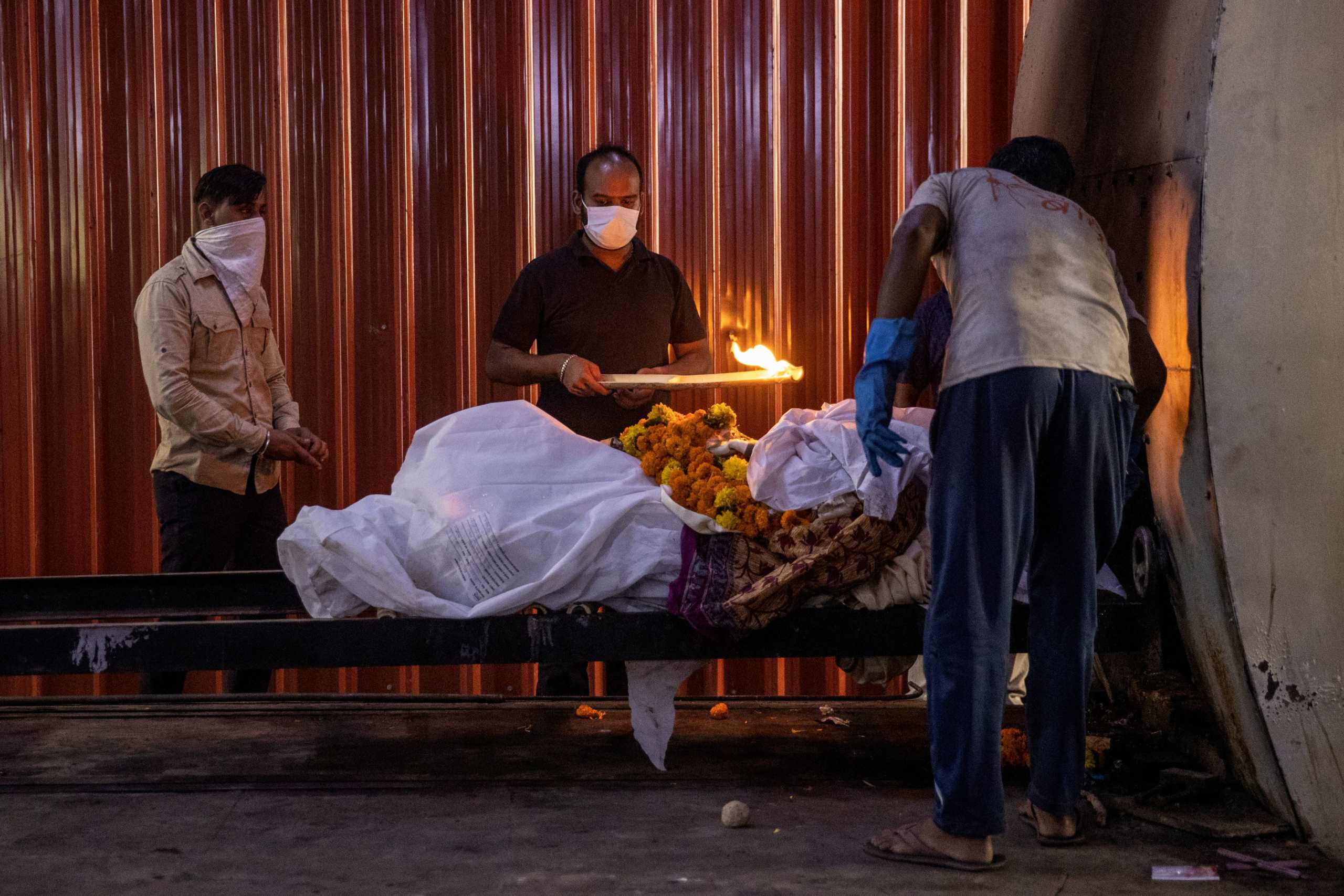 A relative performs the final rites of a woman, who died due to the coronavirus disease (COVID-19), at a crematorium in New Delhi, India, October 3, 2020. REUTERS