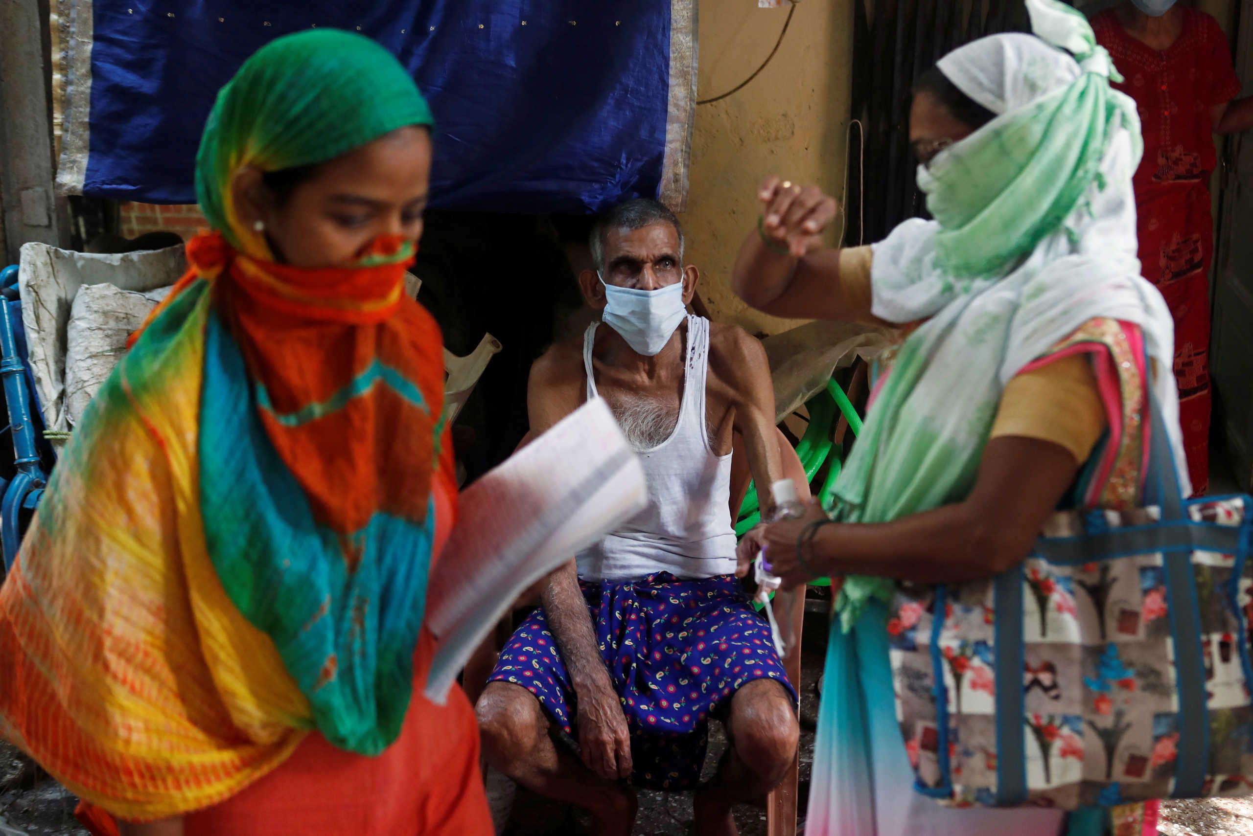 Community health volunteers check the pulse of a resident during a check-up campaign for the coronavirus disease (COVID-19) in Mumbai, India, October 1, 2020. REUTERS