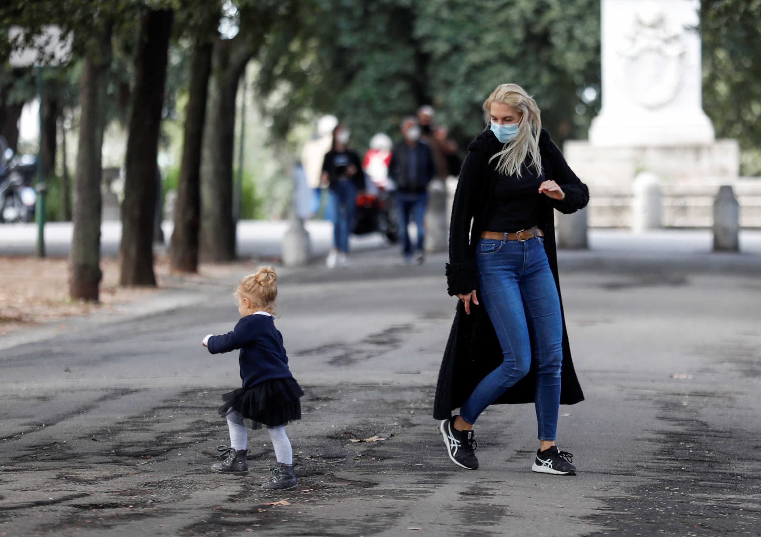 A woman wearing a protective mask plays with a child near Pincio Terrace, amid the outbreak of the coronavirus disease (COVID-19), in Rome, Italy October 13, 2020. REUTERS