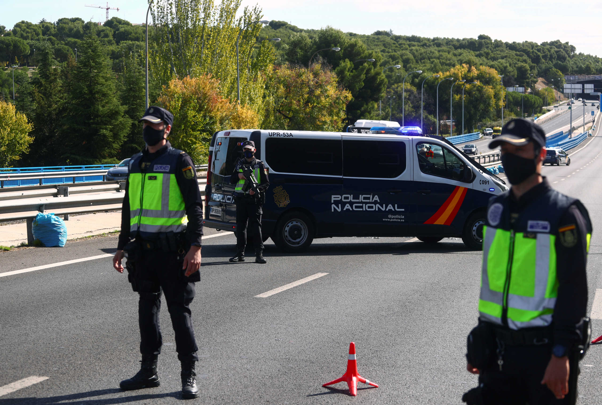FILE PHOTO: Spanish National Police officers wearing protective masks stand at a traffic checkpoint during a partial lockdown amid the outbreak of the coronavirus disease (COVID-19), in Madrid, Spain October 5, 2020. REUTERS
