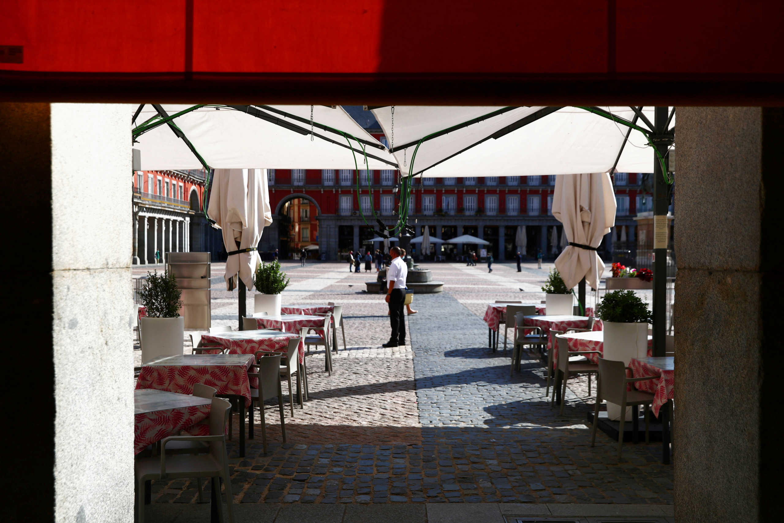 FILE PHOTO: A waiter wearing a protective face mask waits for customers in his terrace at Plaza Mayor square amid the outbreak of the coronavirus disease (COVID-19), in Madrid, Spain October 1, 2020. REUTERS