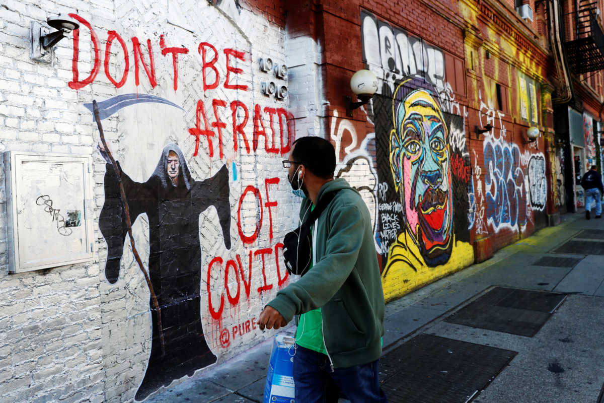 A man walks by murals as the spread of coronavirus disease (COVID-19) continues along Houston Street in New York City, U.S., October 14, 2020. REUTERS