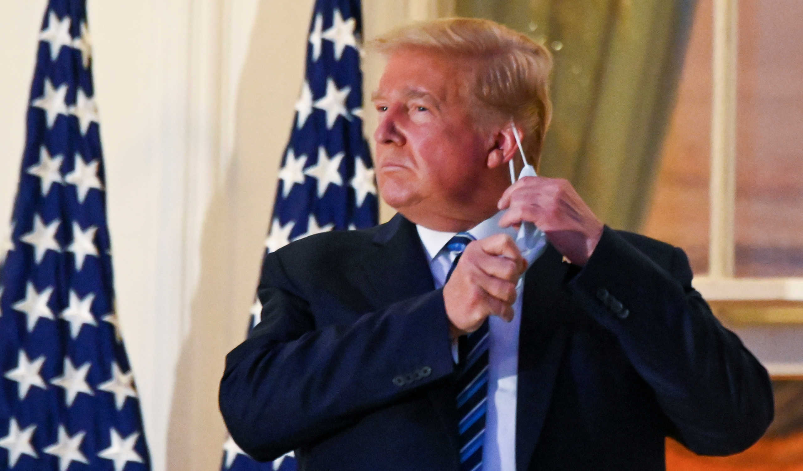 U.S. President Donald Trump pulls off his protective face mask as he poses atop the Truman Balcony of the White House after returning from being hospitalized at Walter Reed Medical Center for coronavirus disease (COVID-19) treatment, in Washington, U.S. October 5, 2020. REUTERS