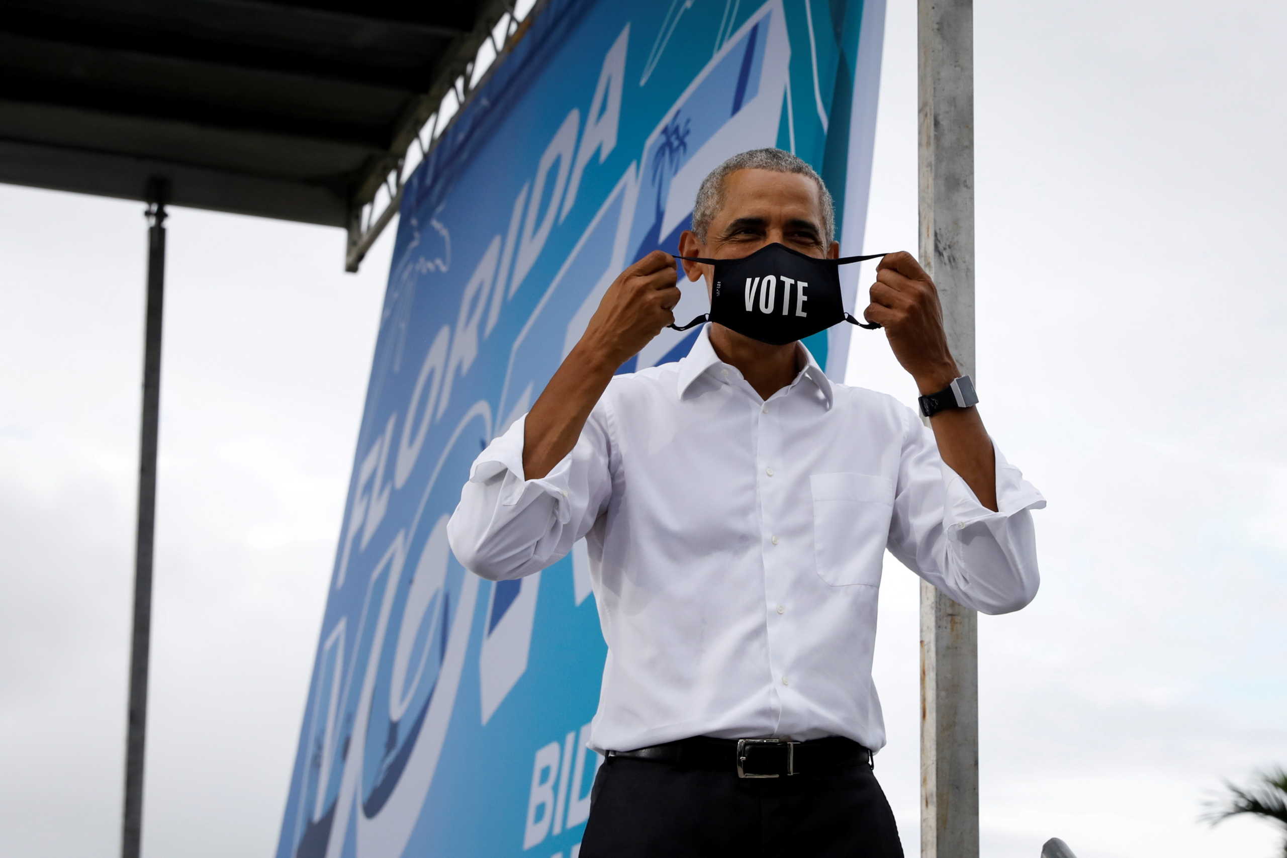 Former U.S. President Barack Obama puts on a "Vote" mask after speaking during a campaign rally on behalf of Democratic presidential nominee and his former Vice President Joe Biden in Miami, Florida, U.S., October 24, 2020. REUTERS