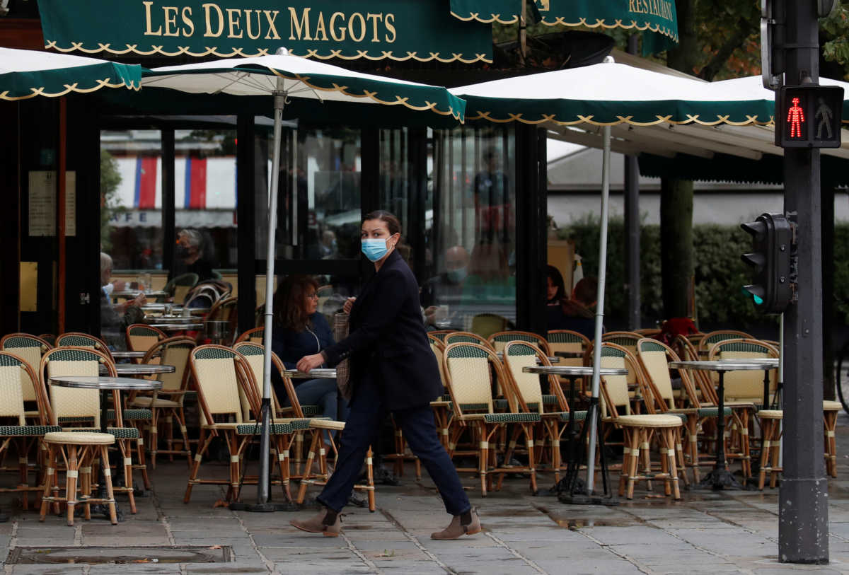 A woman wearing a protective face mask walks past the cafe and restaurant Les Deux Magots in Paris, during the announcement of new Covid restrictions by Paris authorities as the coronavirus disease (COVID-19) outbreak continues in France, October 5, 2020. REUTERS